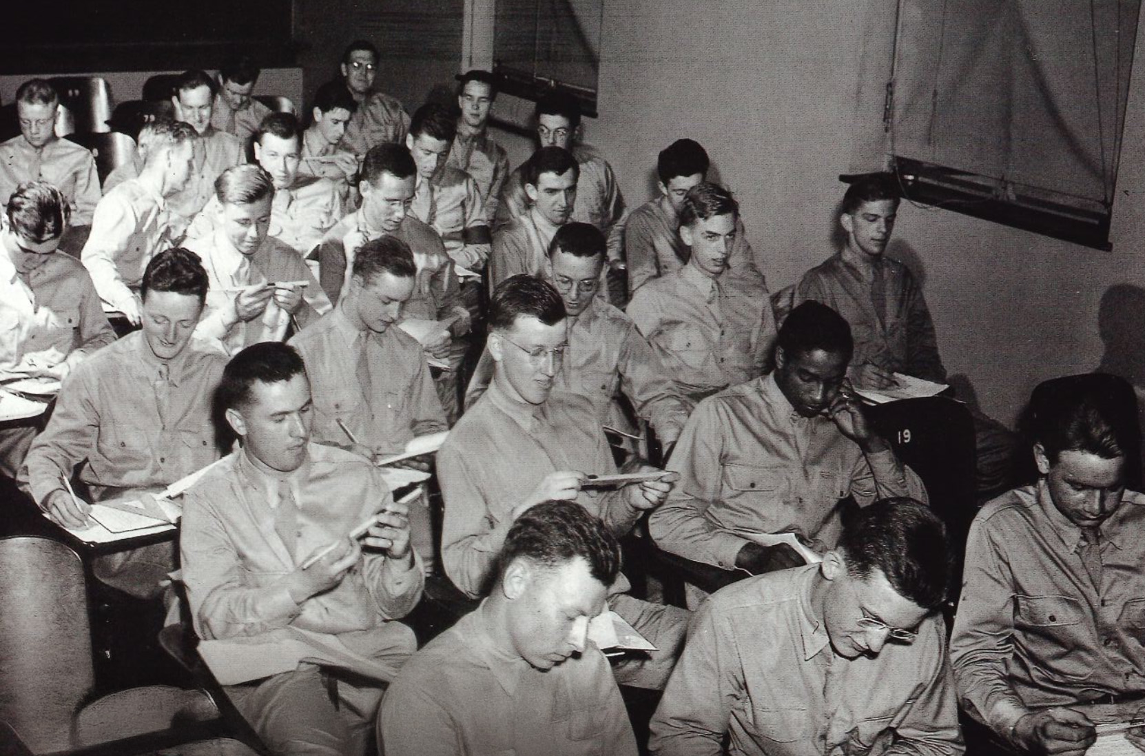 black and white photo of men in uniform sitting at desks by Penn State Archives