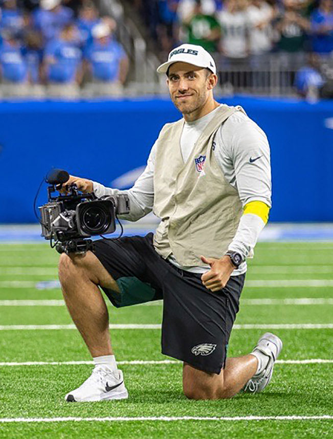 Rotondi in Eagles gear on the football field with camera, courtesy