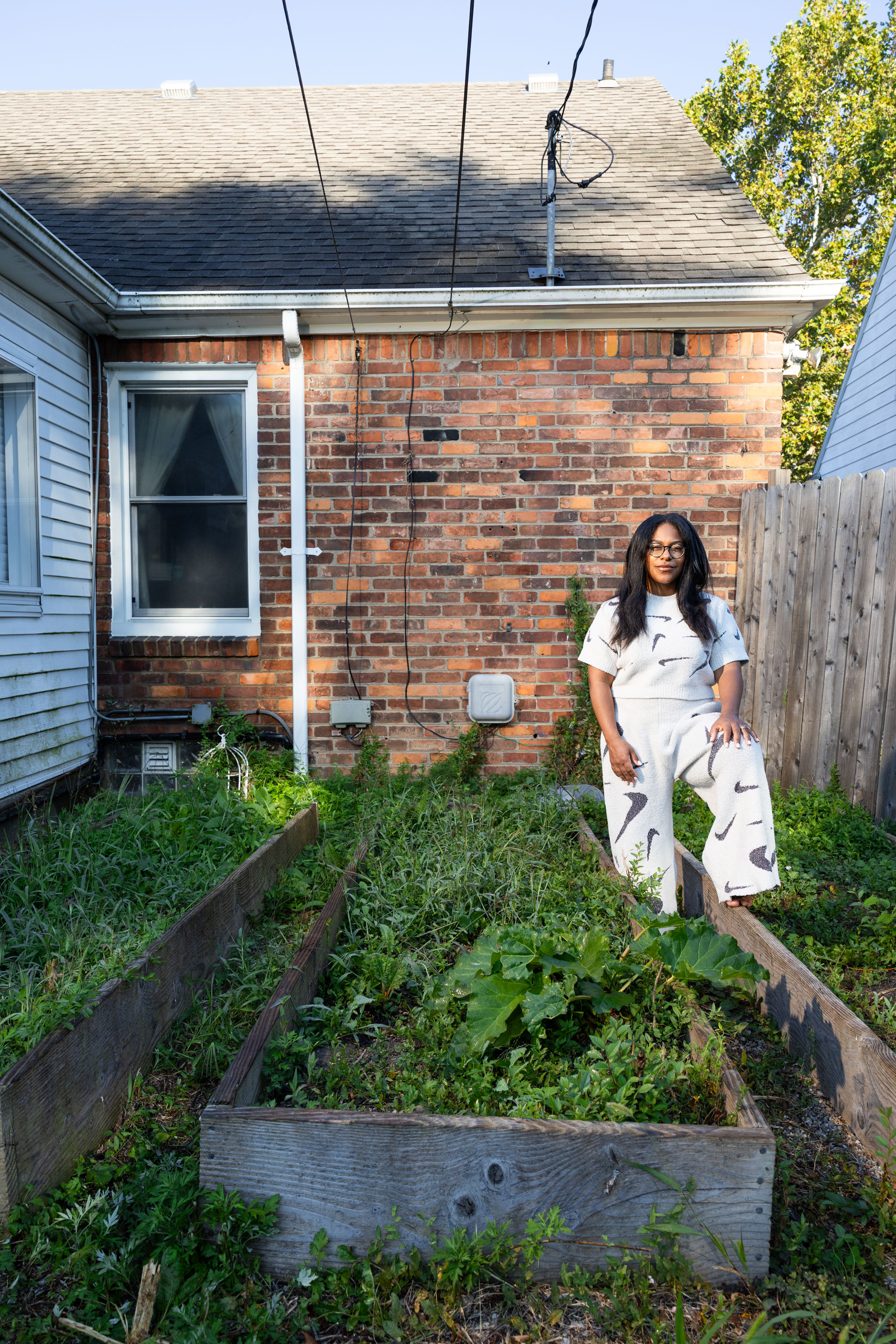 Lyndsay Green standing beside a raised garden bed in her Detroit backyard,  photo by Michael Lewis
