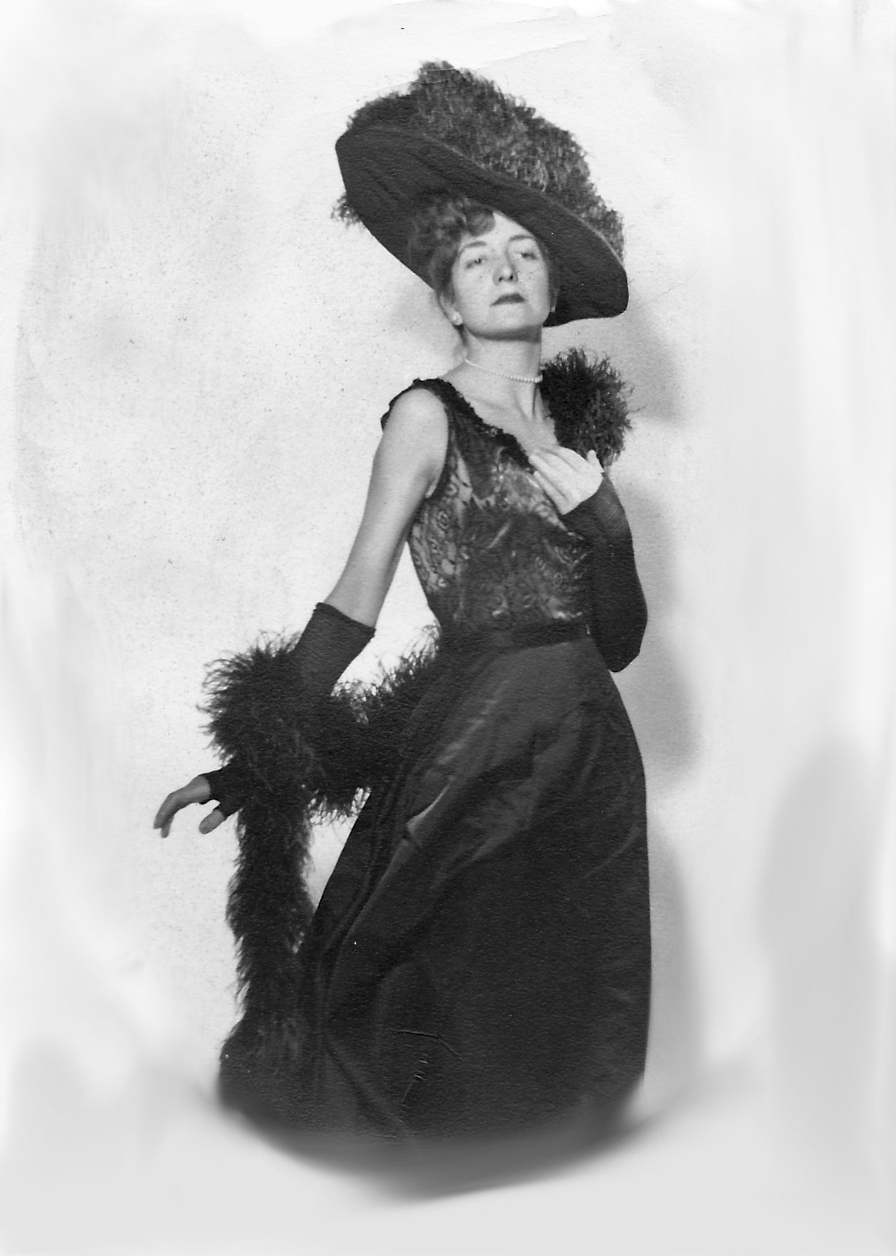 black and white photo of Helen Manfull in a costume of a gown, feather boa, and hat, courtesy