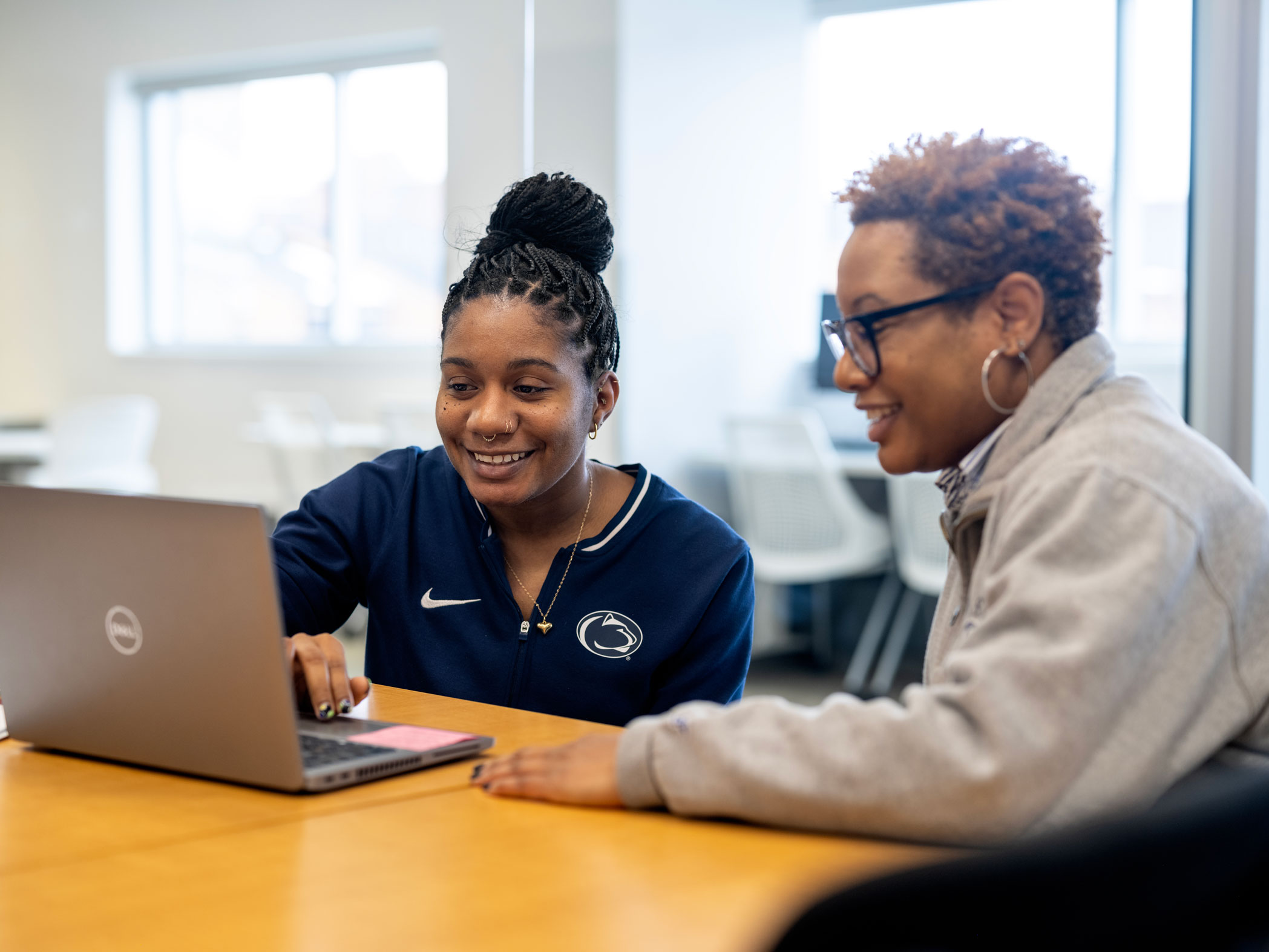 photo of an alum and a career services specialist at a table with laptop, courtesy
