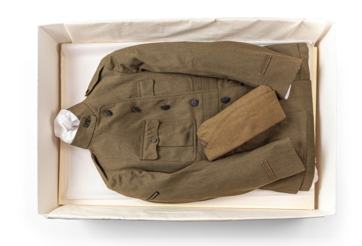 Photo of Ernest Hemingway's World War I jacket and cap in a white fabric lined display box. Photo by Nick Sloff '92 A&A.
