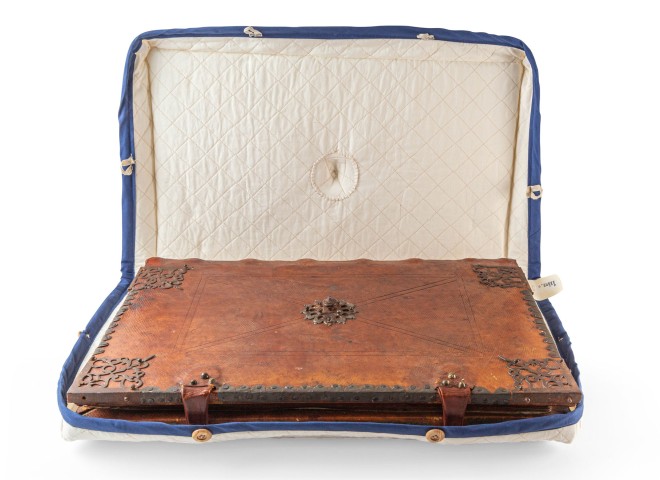 Closeup photo of a brown leather bound book with metal adornments inside a white quilted case trimmed in royal blue. Photo by Nick Sloff '92 A&A.