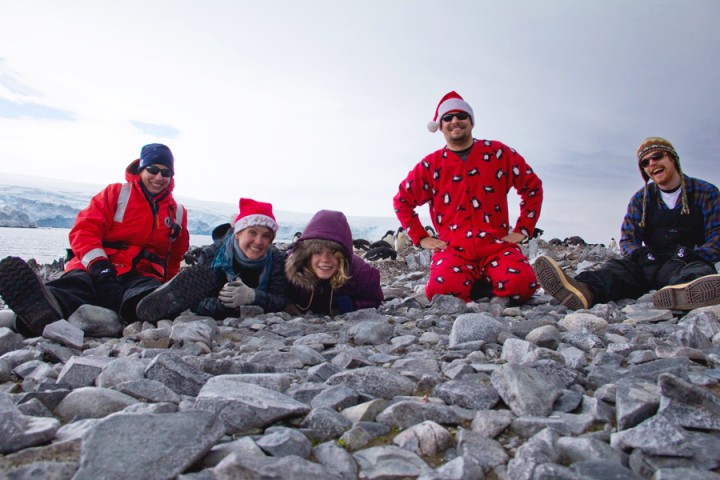 Christmas in Antarctica, group of people in festive cold weather gear, one wearing a Santa hat, photo by Zena Cardman