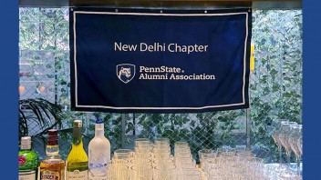 Banner for New Delhi chapter of the Penn State Alumni Association over a table of cocktails