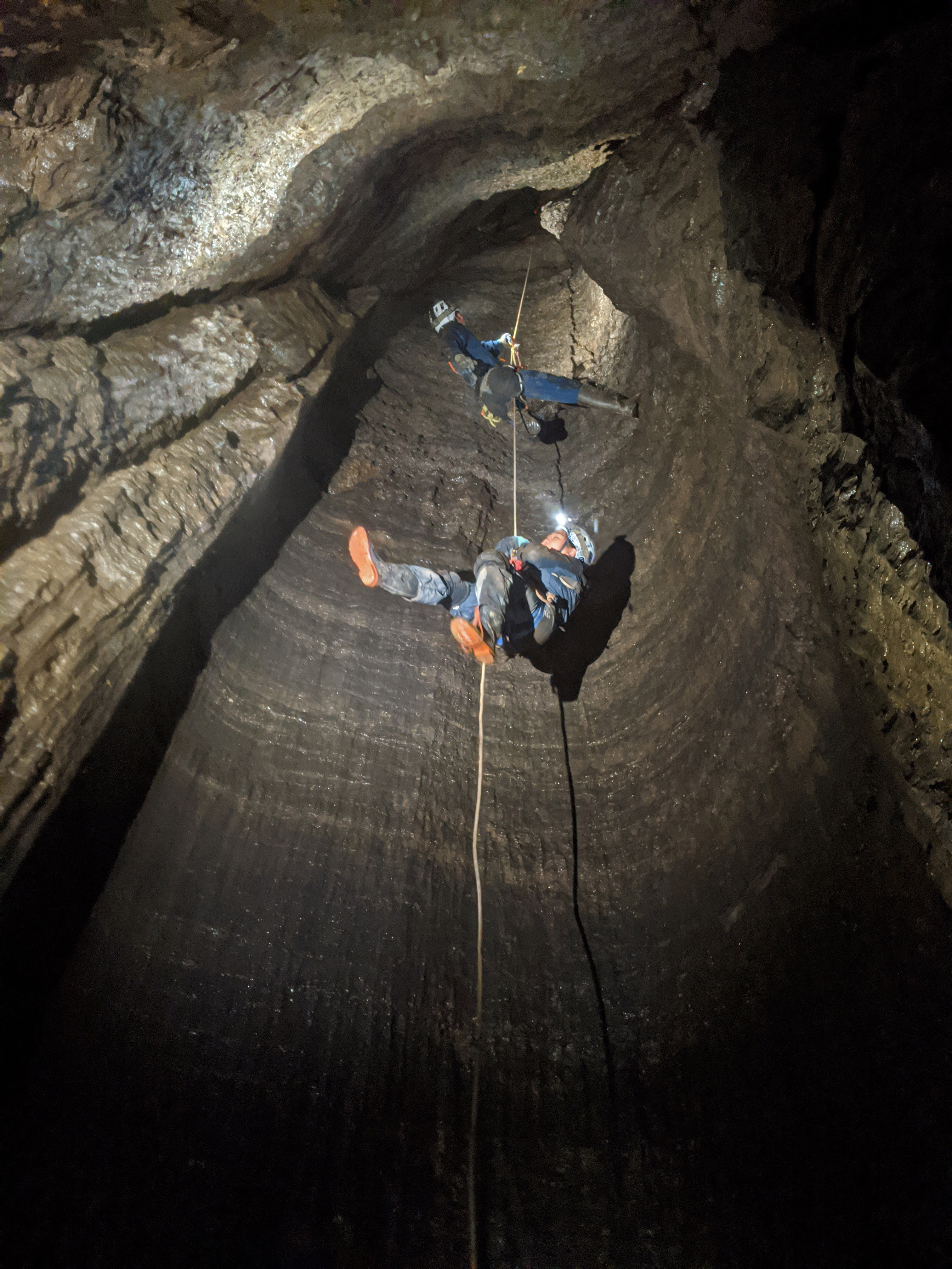 Cavers rappelling down a hole