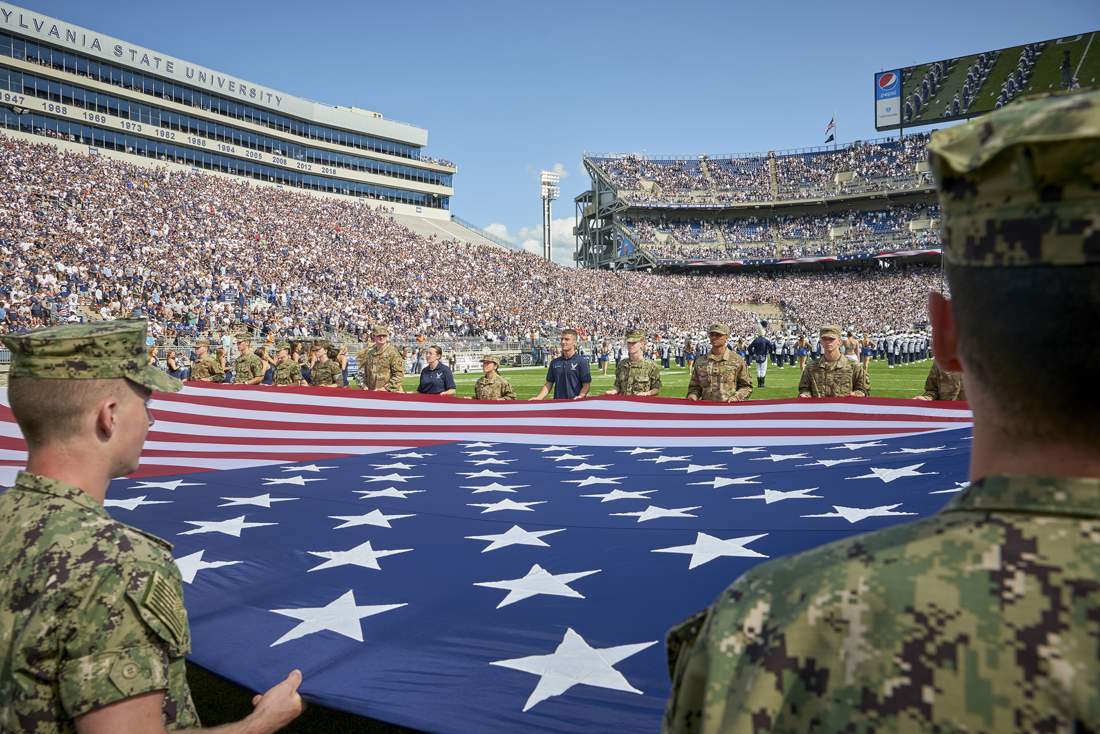 Military personnel with American flag in Beaver Stadium