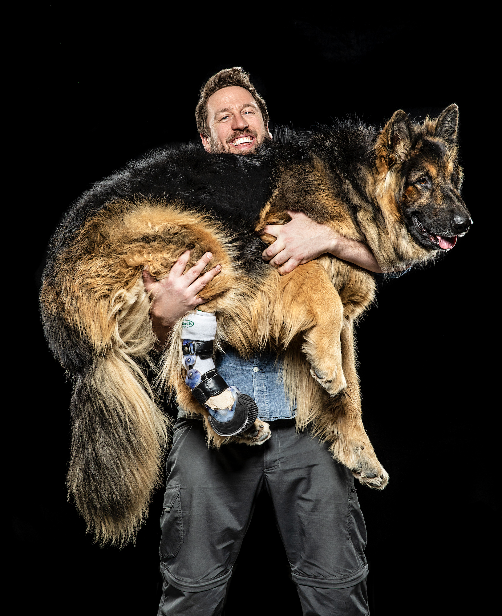 Derrick Campana holding Petey, a kind shepherd who was born with one foot missing, photo by Steve Boyle