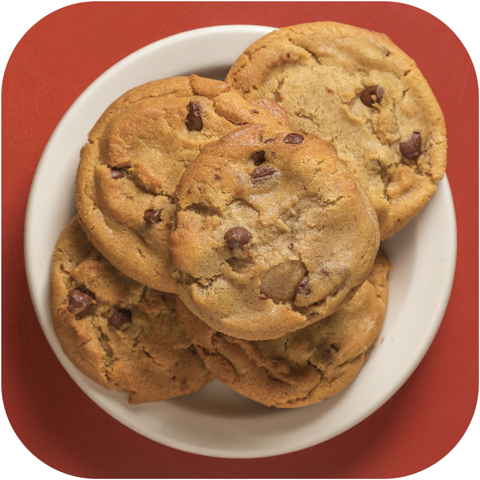 plate of chocolate chip cookies on a red surface
