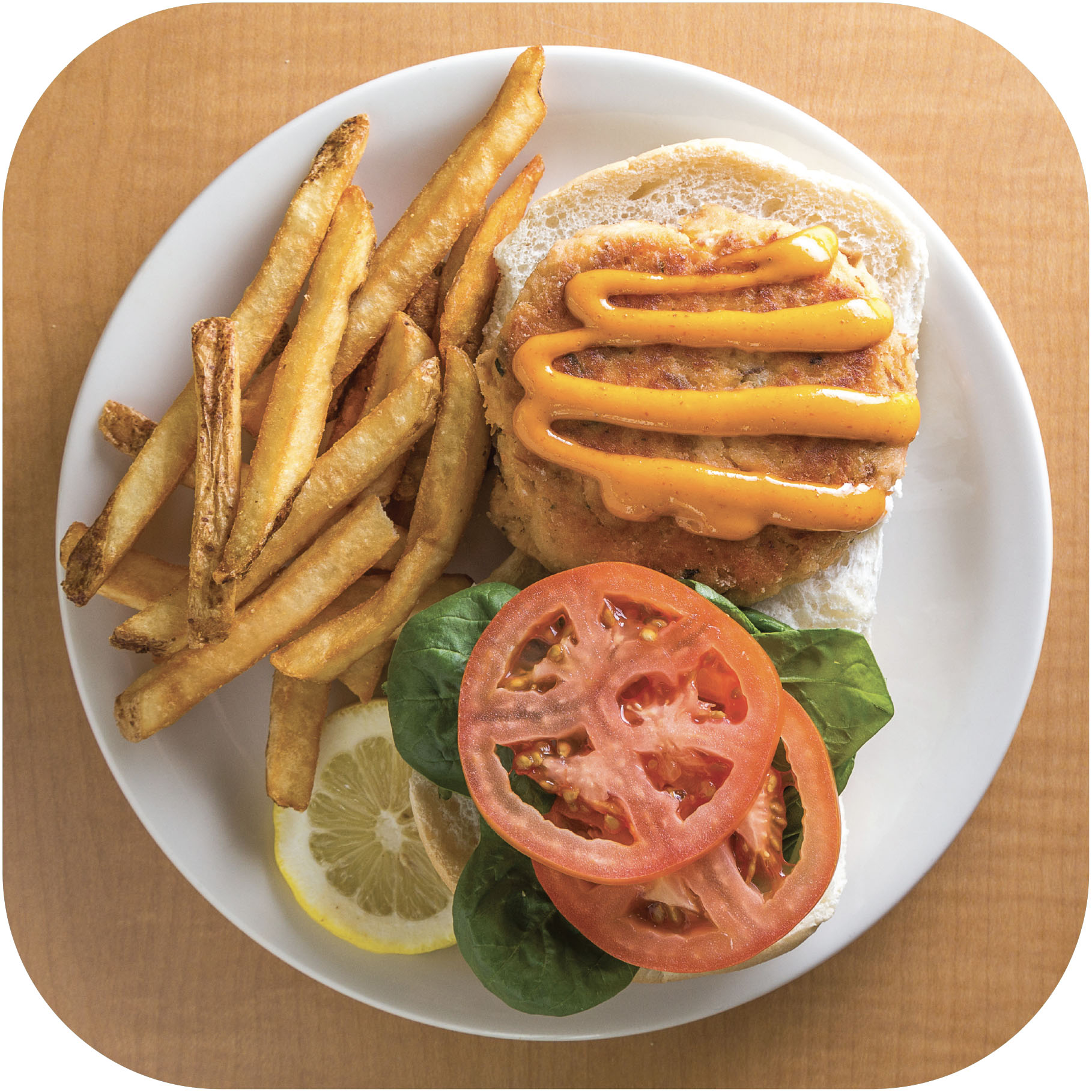open face salmon burger with lettuce and tomatoes beside fries