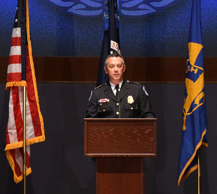 Gallagher standing in military uniform behind a podium with American flag, courtesy