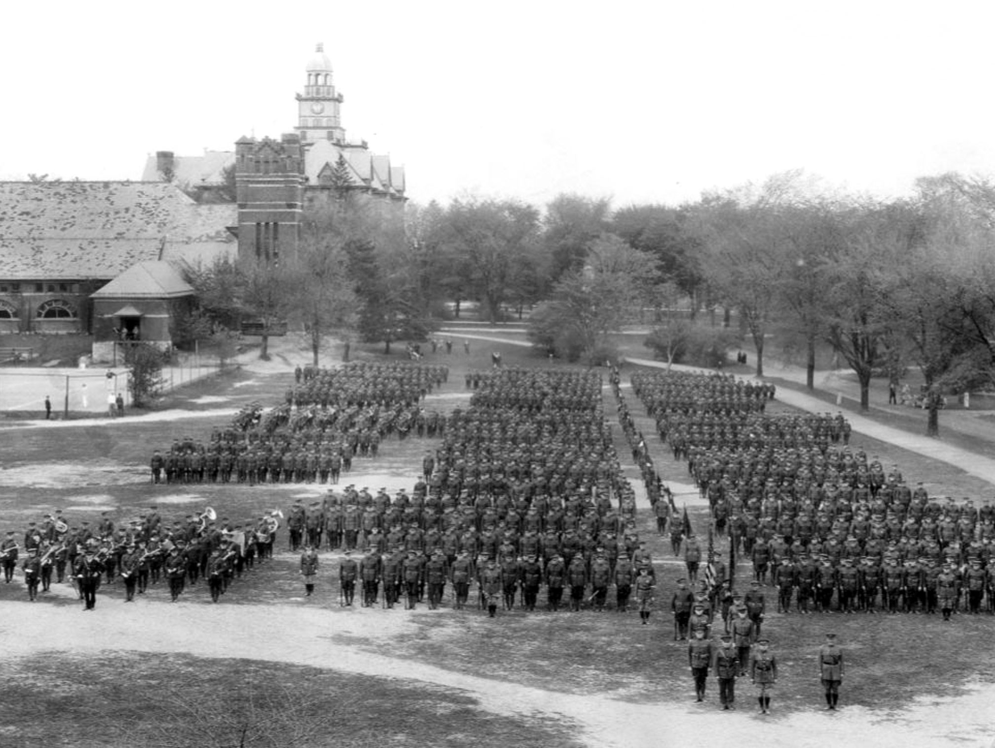 black and white photo of Cadet Bugle Corps accompanying the Student Army Training Corps Cadets in 1918 with Old Main in the background, by Penn State Archives