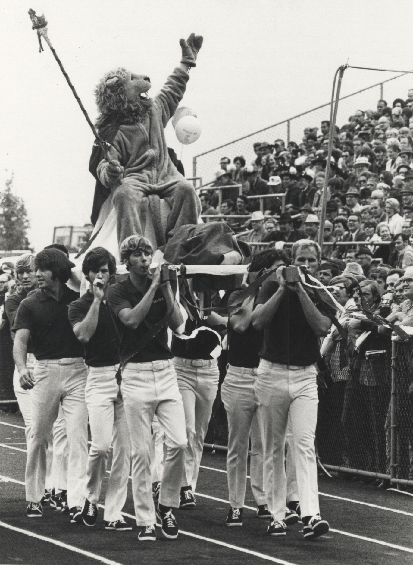 black and white photo of the Nittany Lion with a mane being carried by a group of students