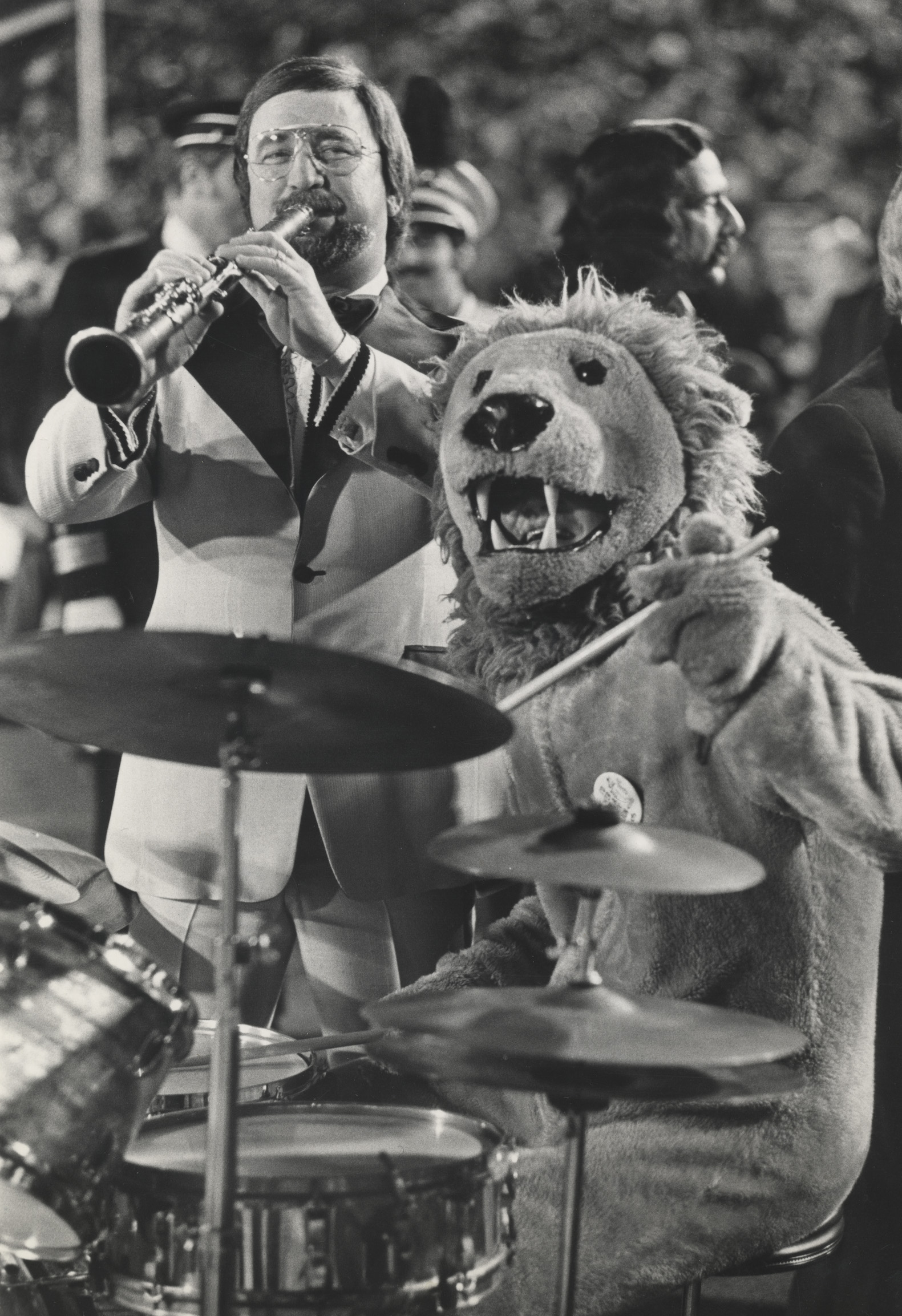 black and white photo of the Nittany Lion playing drums with the marching band