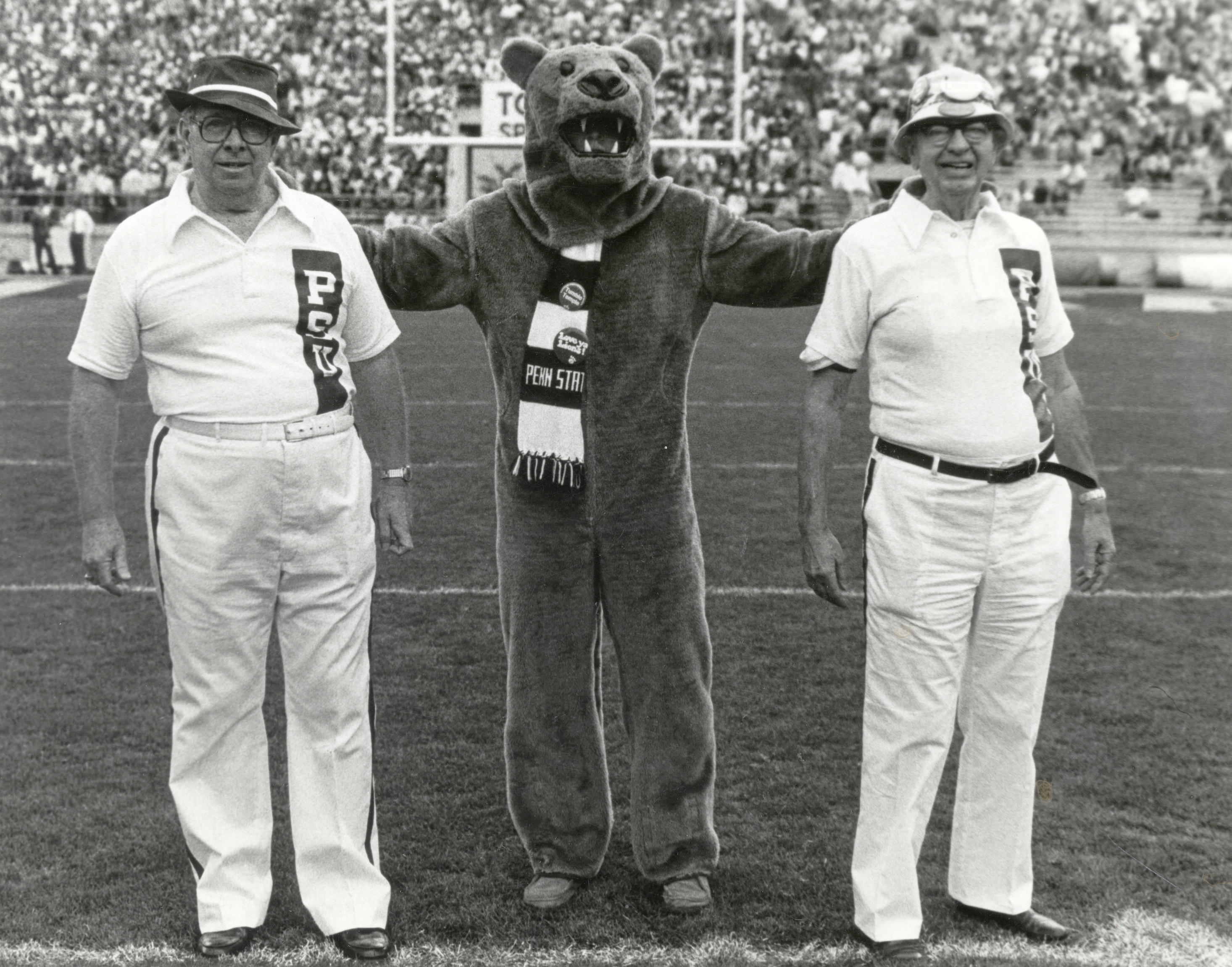 black and white photo of the Nittany Lion standing with two men on the football field