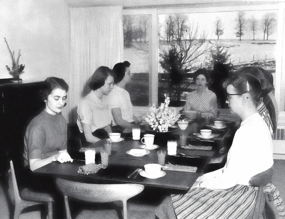 black and white photo of a group of women sitting around a table enjoying a meal