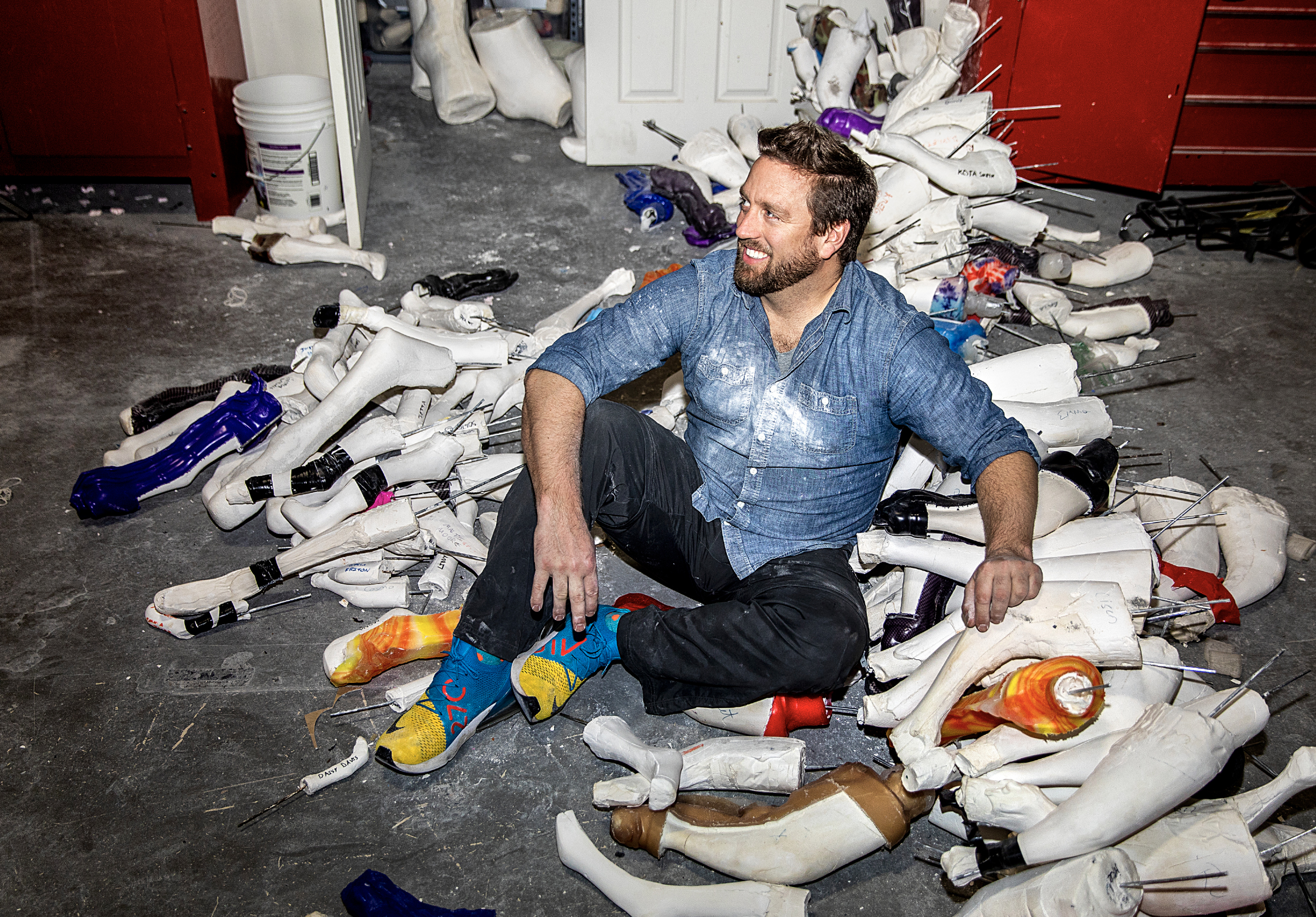 Campana sitting on the floor with dozens of prosthetics he's created