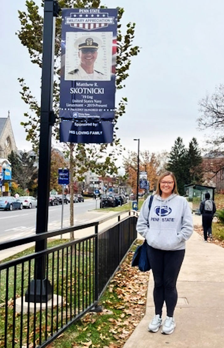 Skotnicki posing under a military banner, courtesy