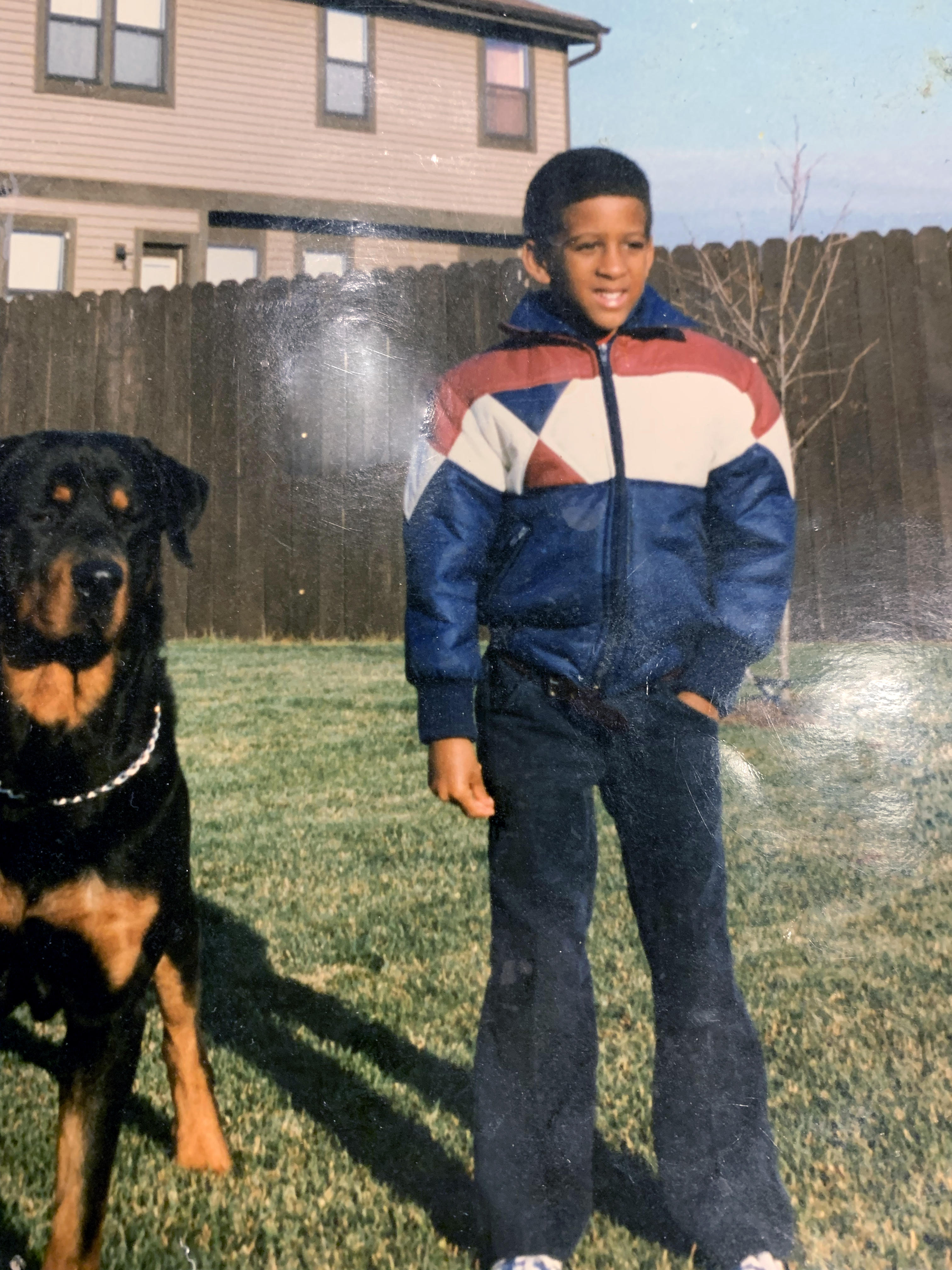 Calvin Booth as a child in a fenced backyard with a large dog, courtesy
