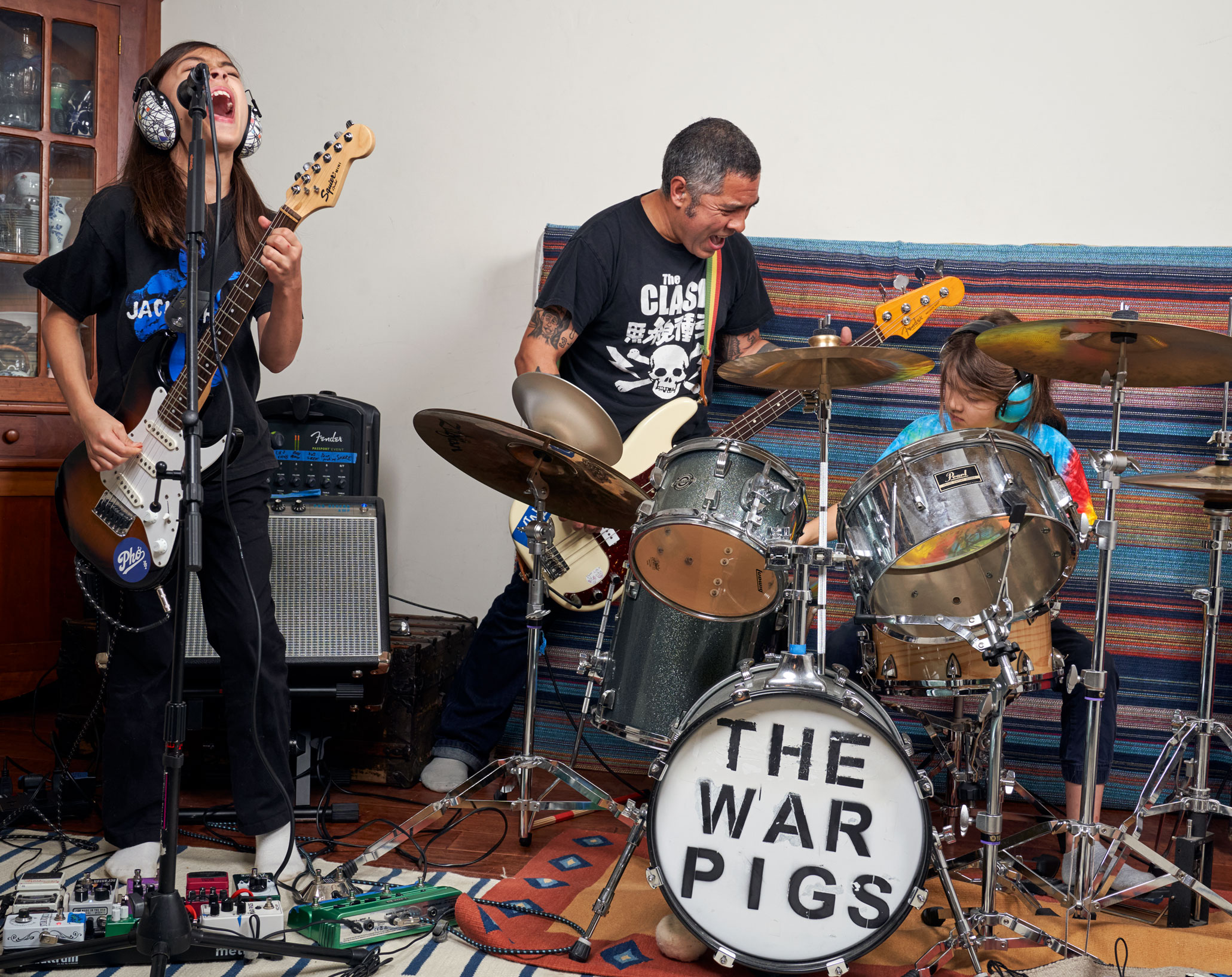 De Leon playing guitar while his children play guitar and drums, photo by Gregg Segal
