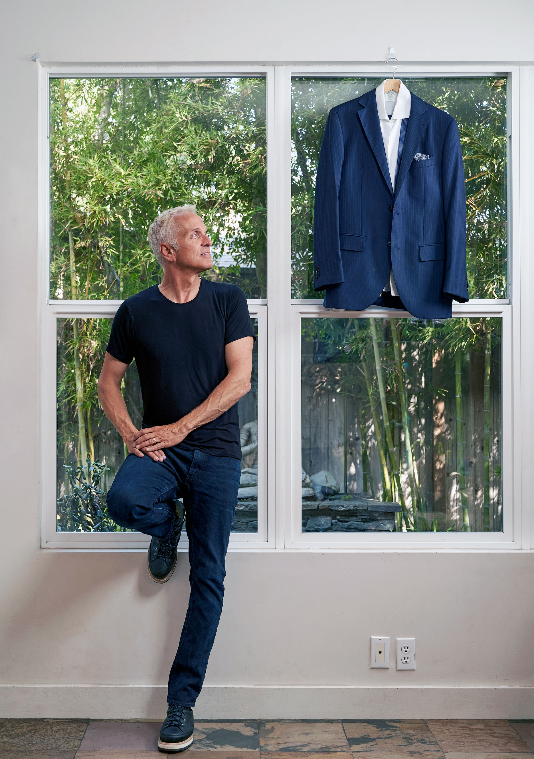 Patrick Fabian standing in front of a window looking left to a blue suit he wore in Better Call Saul, photo by Gregg Segal