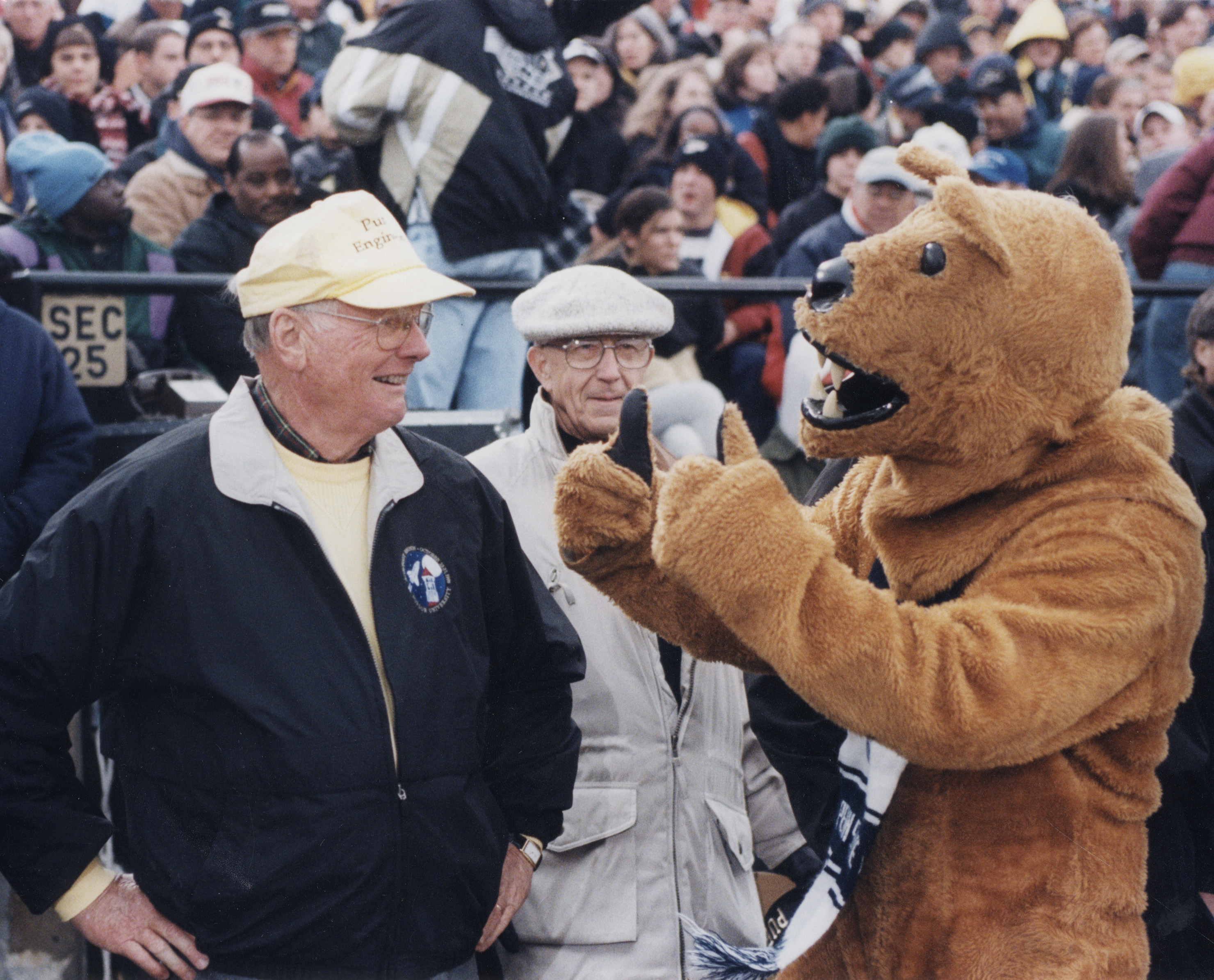 the Nittany Lion talking to fans on the sideline at a football game