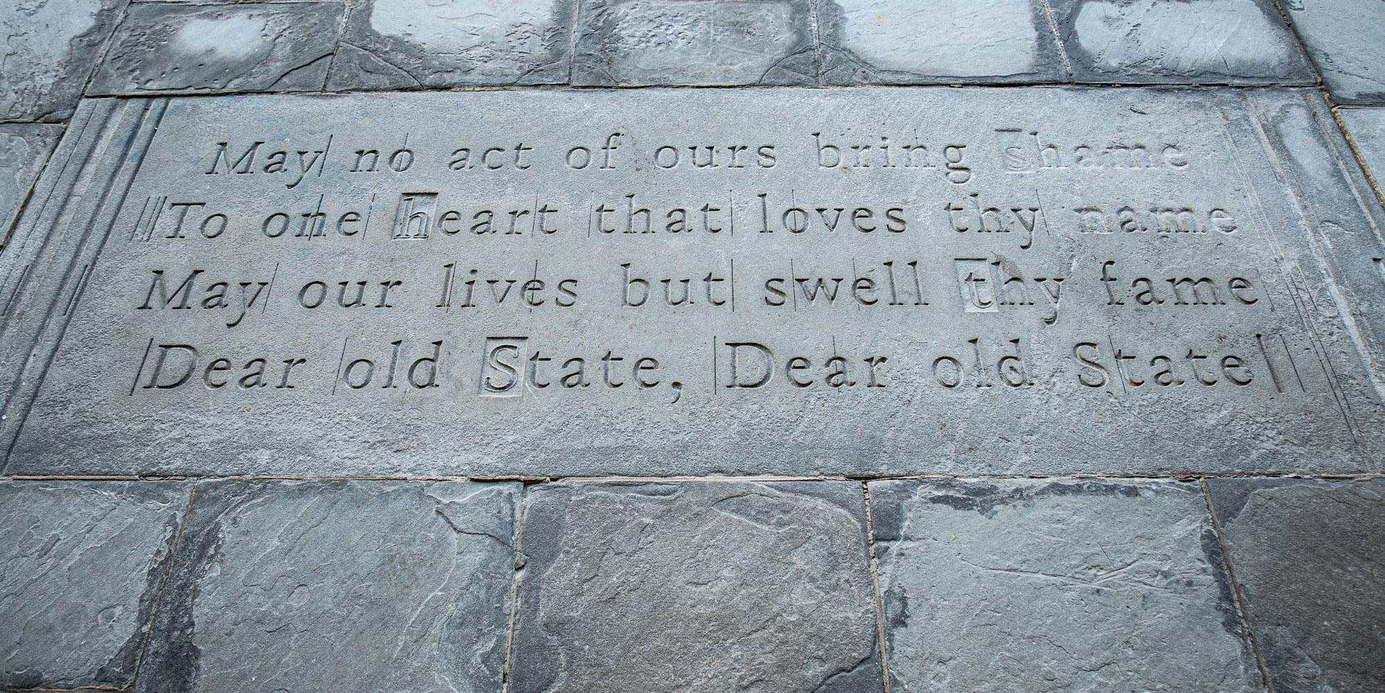 photo of the fourth verse of the alma mater carved into the stone porch floor at the main entrance of the Hintz Family Alumni Center, by Cardoni