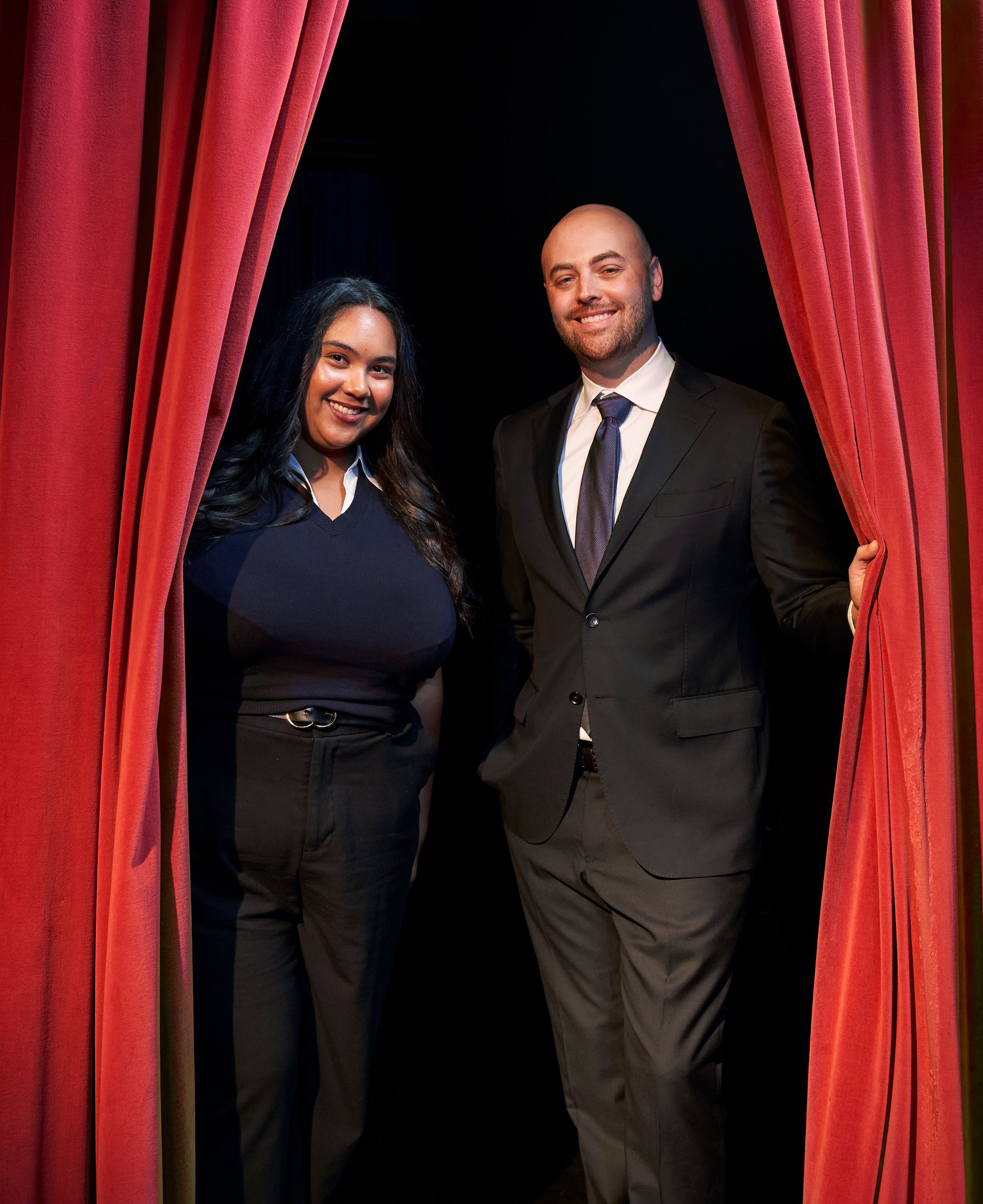 photo of Forman and Pepperman standing as they part a red curtain on stage by Gregg Segal