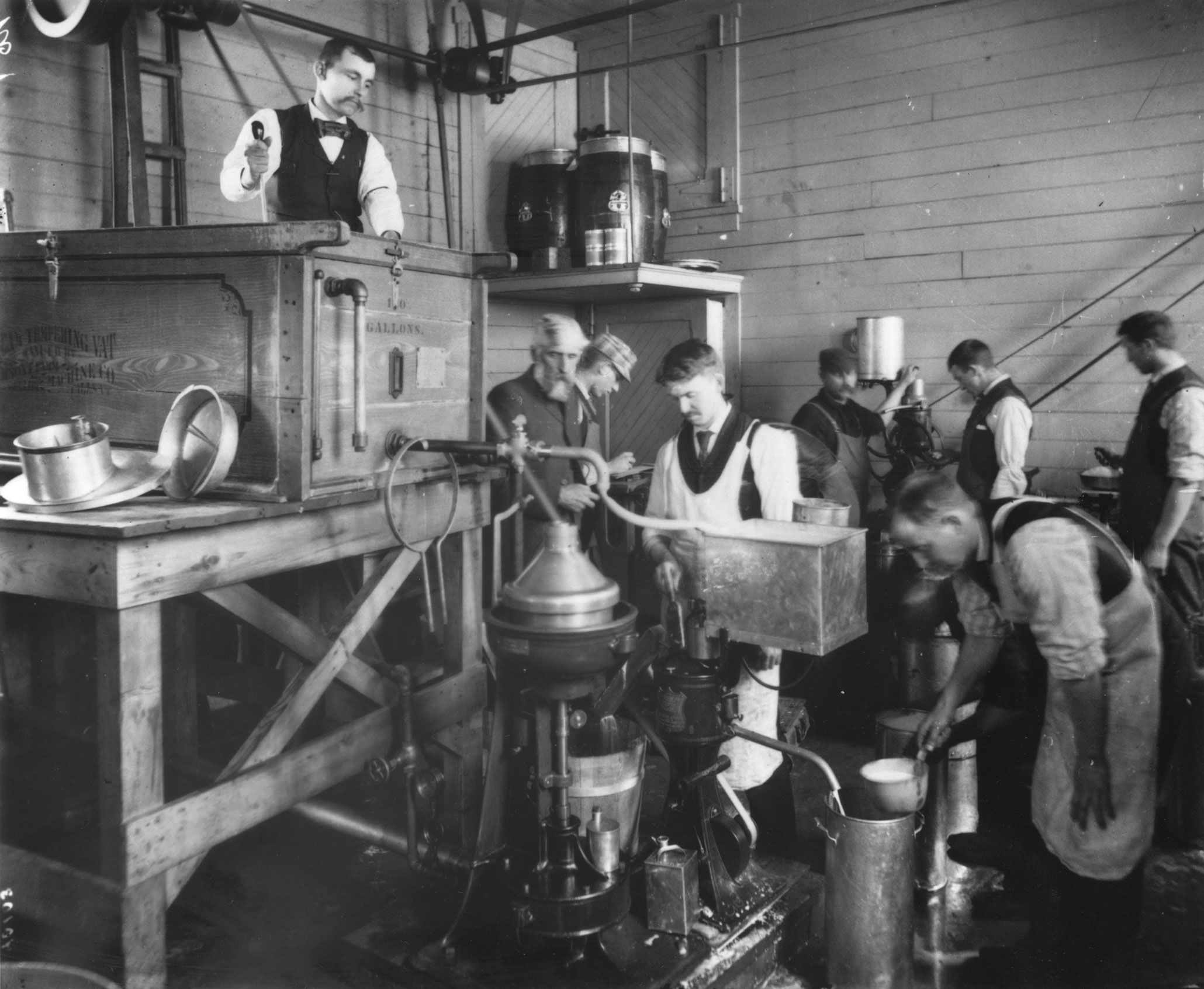 black and white photo of half a dozen men making cream and butter in a barn, Penn State Archives