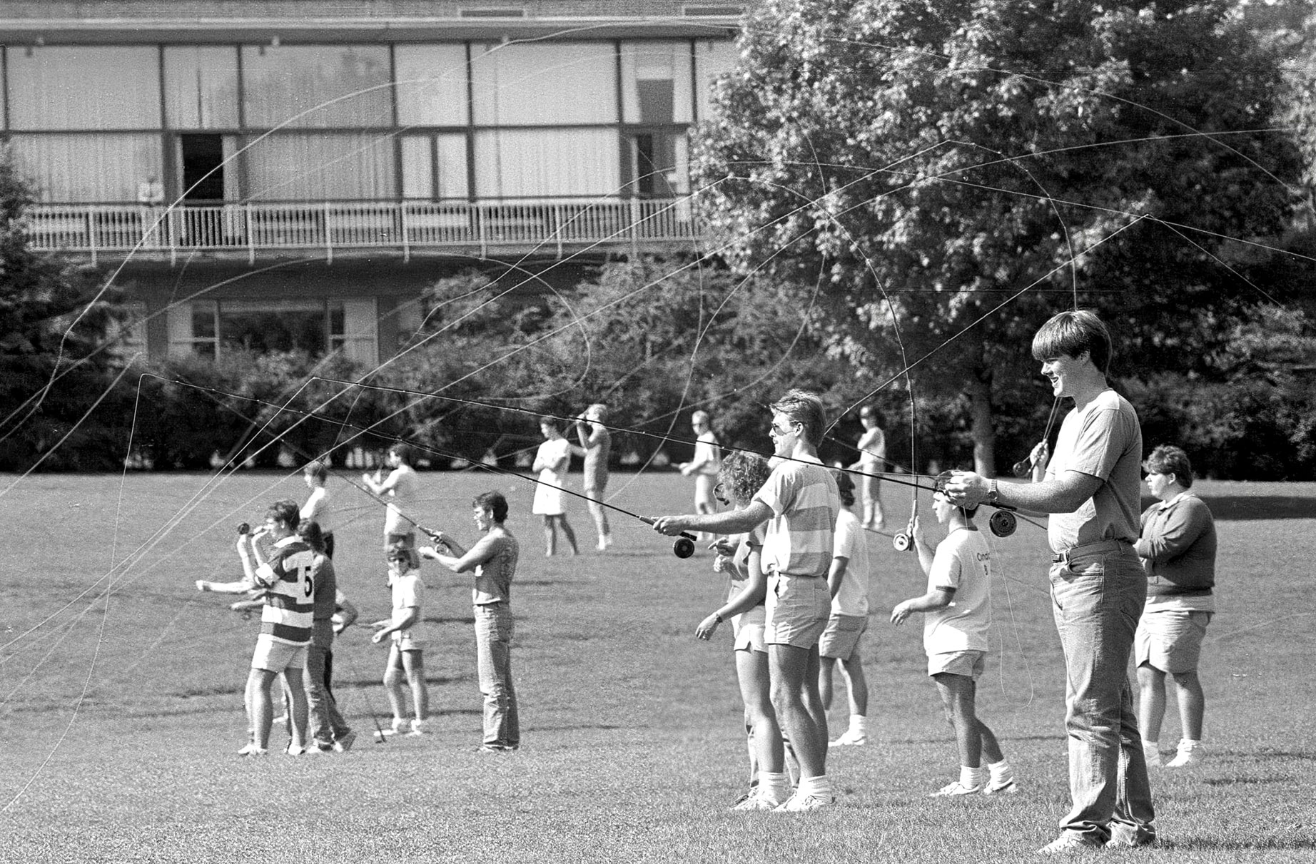 black and white photo of a dozen or so students practicing fly fishing on the HUB lawn by Pat Little 