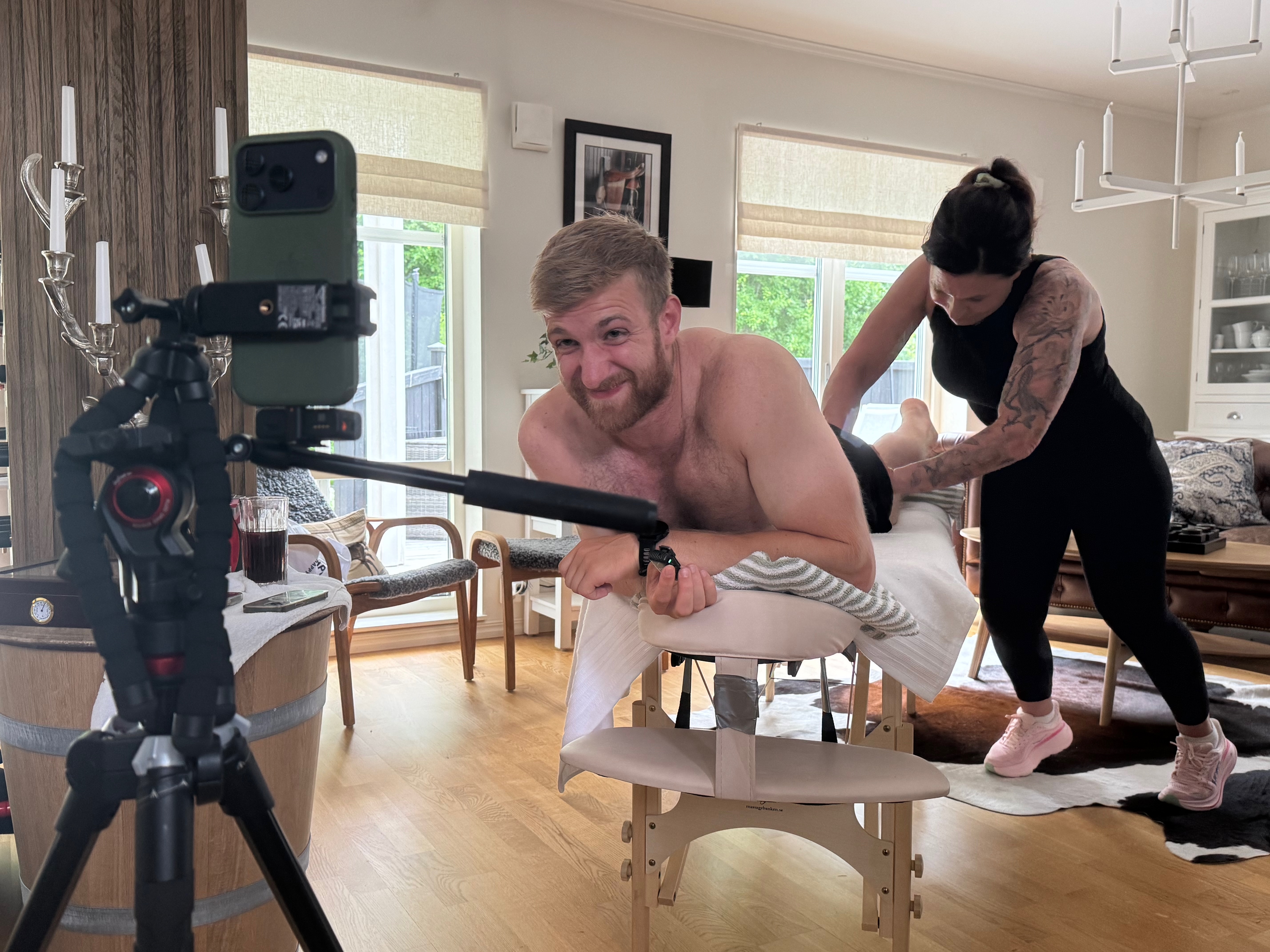 Hollingham wincing in pain on massage table during livestream at Lovisa's family home, courtesy
