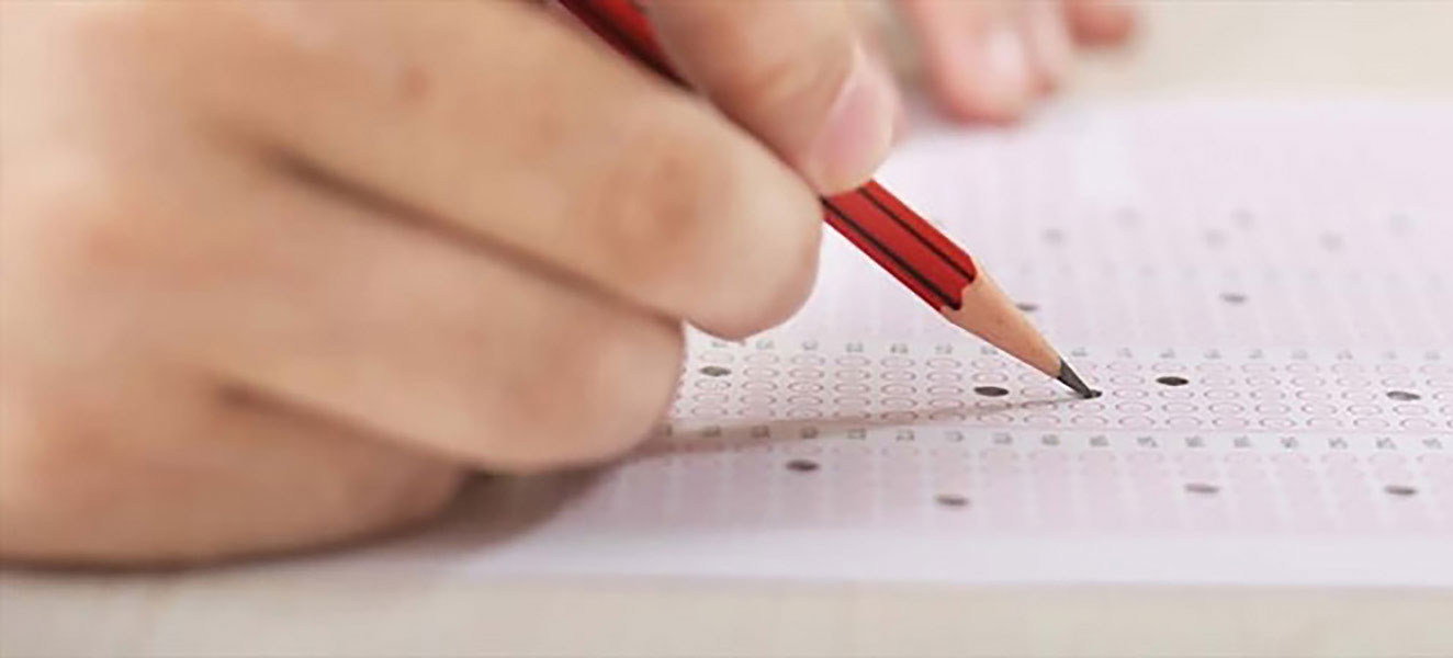 closeup photo of a hand holding a pencil and filling in a circle on a standardized test