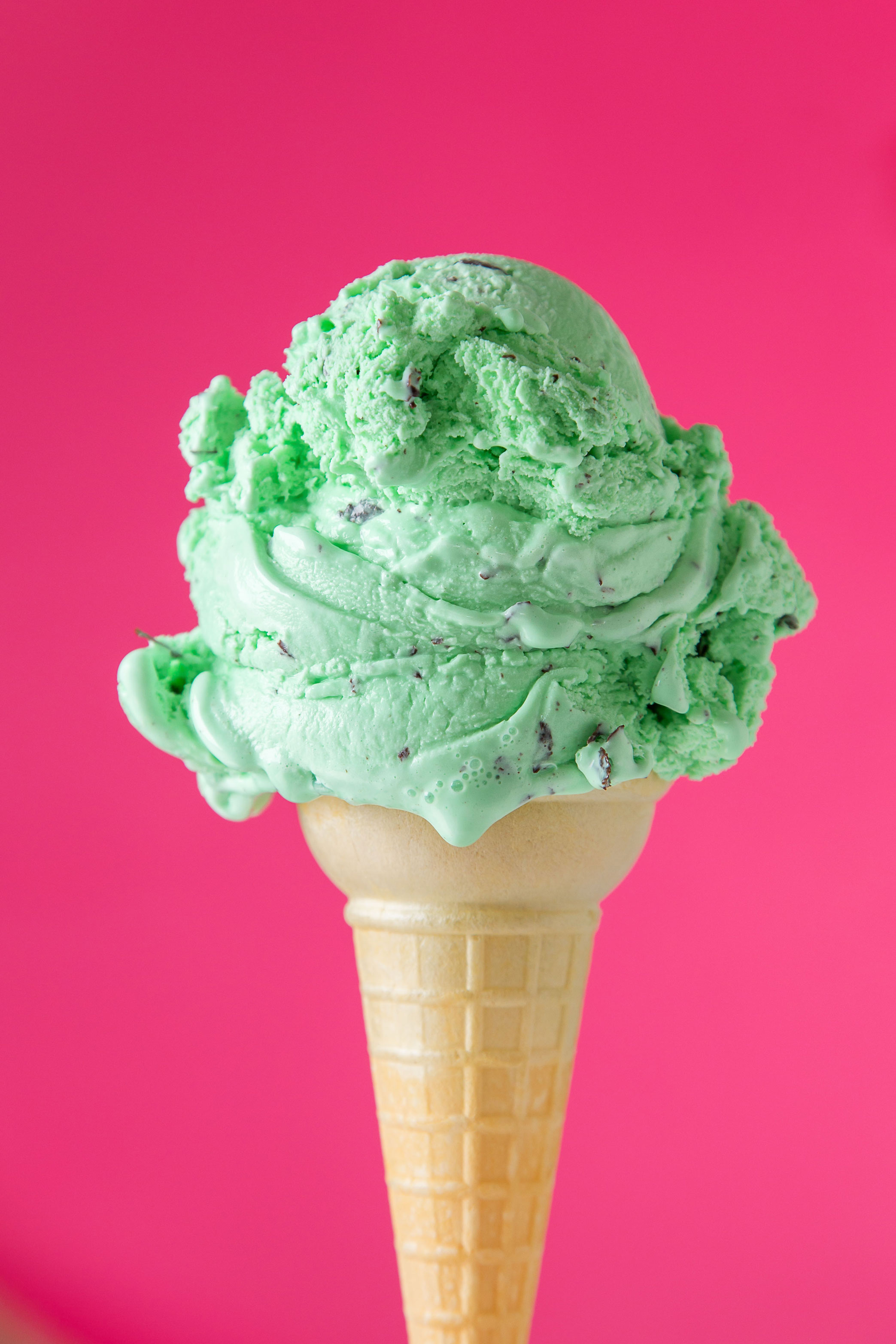 a cone of mint chocolate chip ice cream on a hot pink background by Nick Sloff '92 A&A