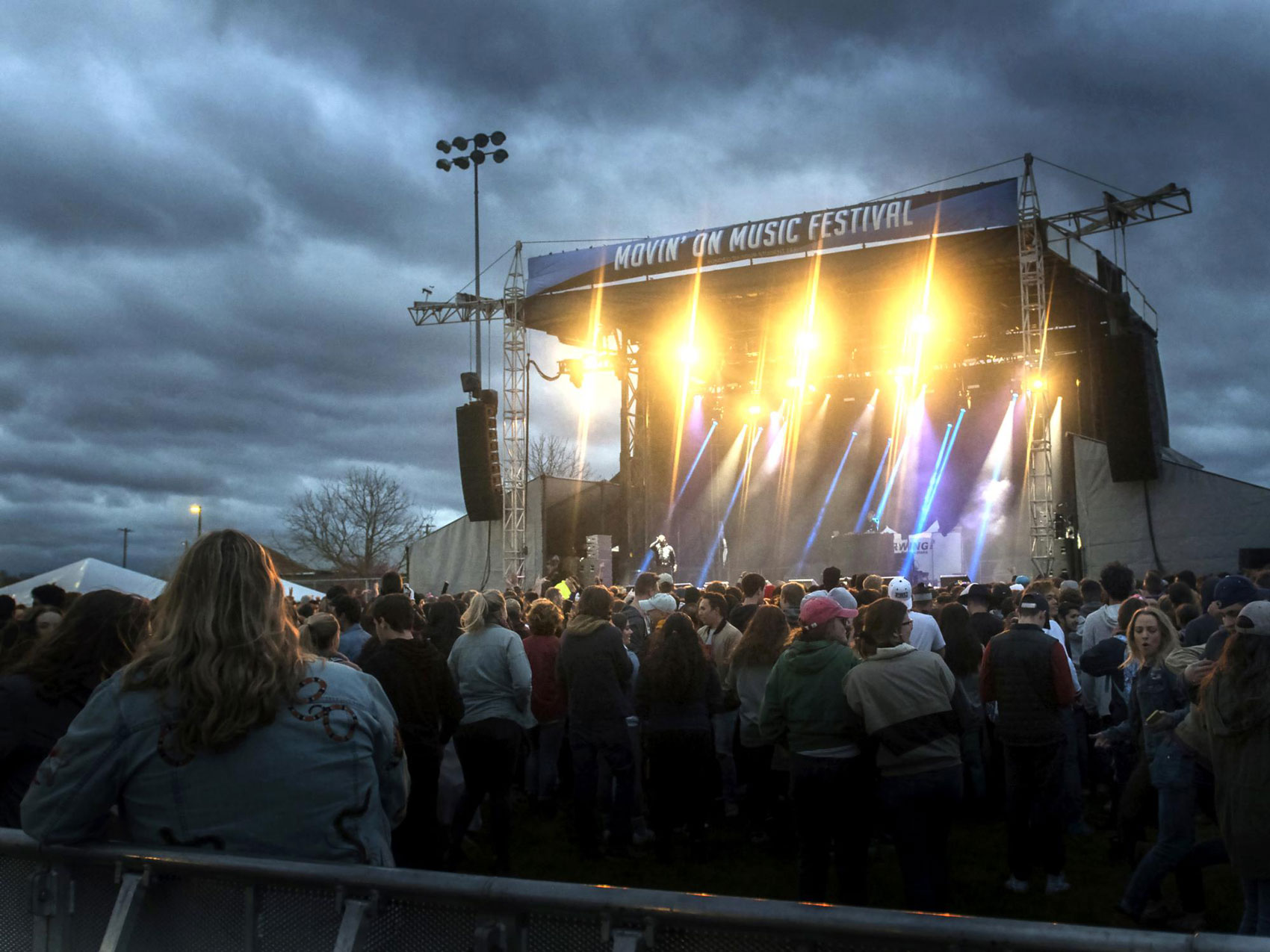 photo of students standing on HUB lawn under darkening cloudy skies with lit up Movin' On stage in background courtesy Movin' On instagram account