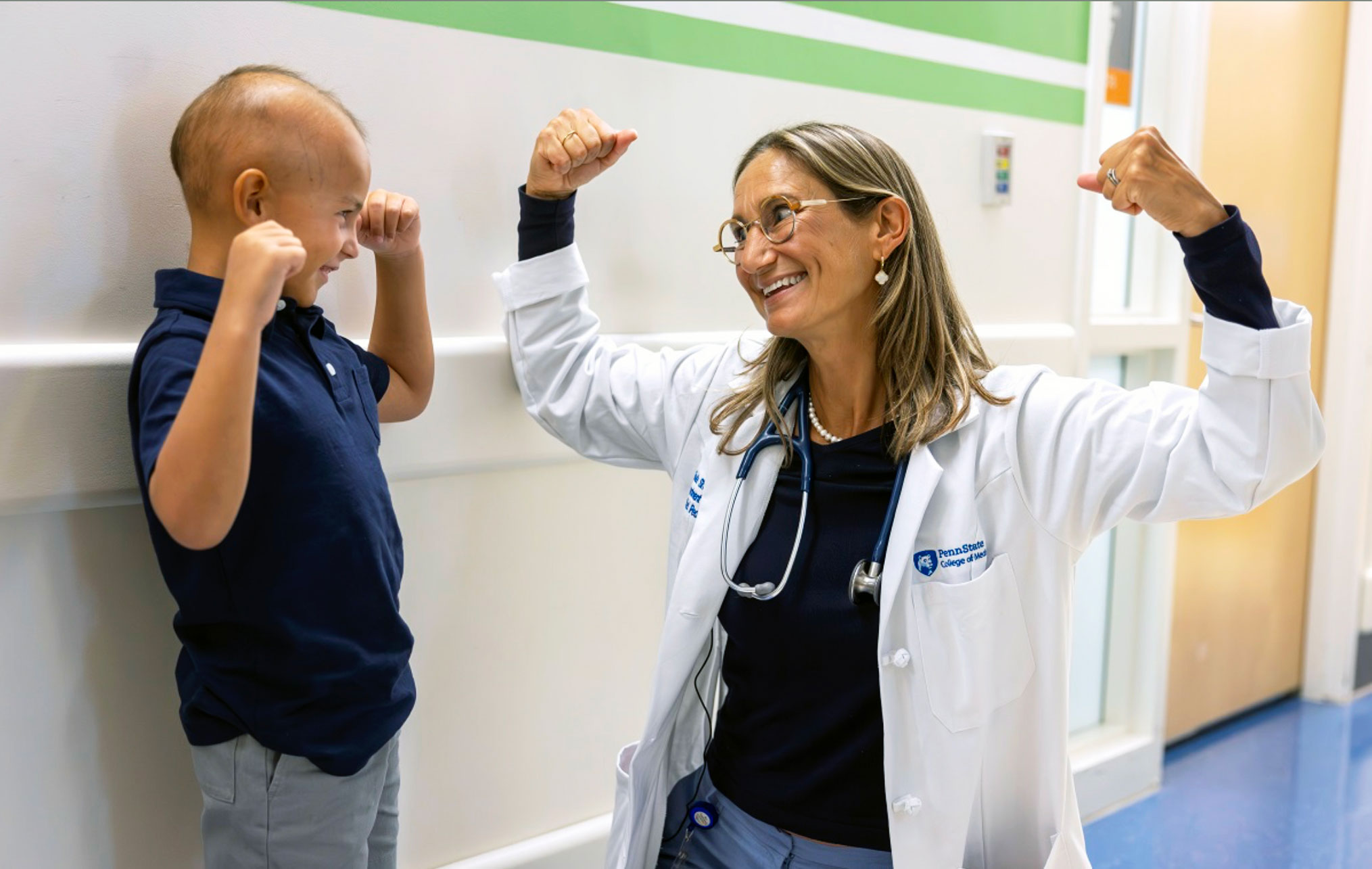 Sholler flexing muscles with a young patient, photo by Penn State