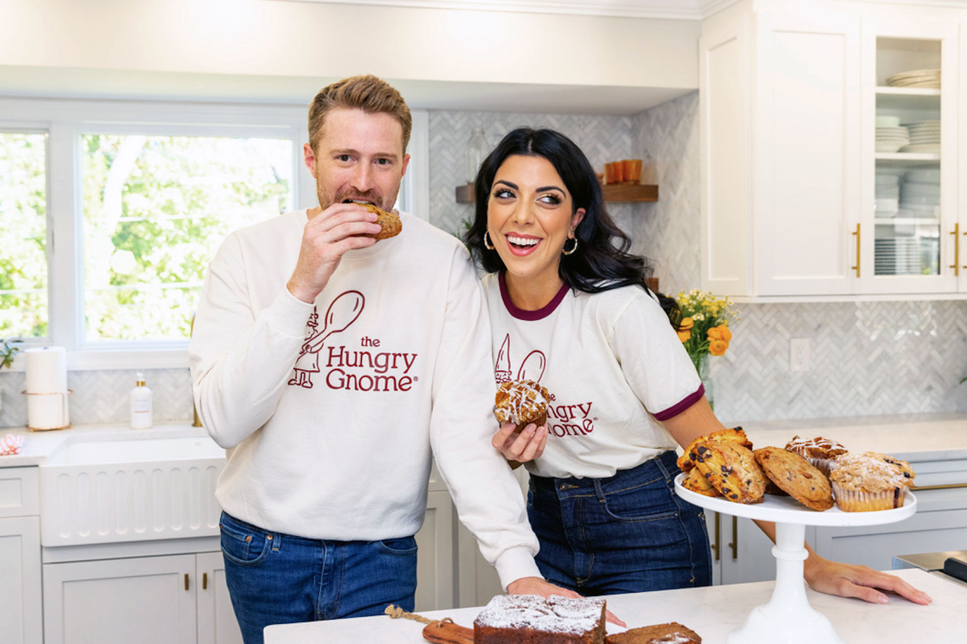 Dan and Danielle Sepsy in their kitchen eating scones and wearing Hungry Gnome apparel, courtesy