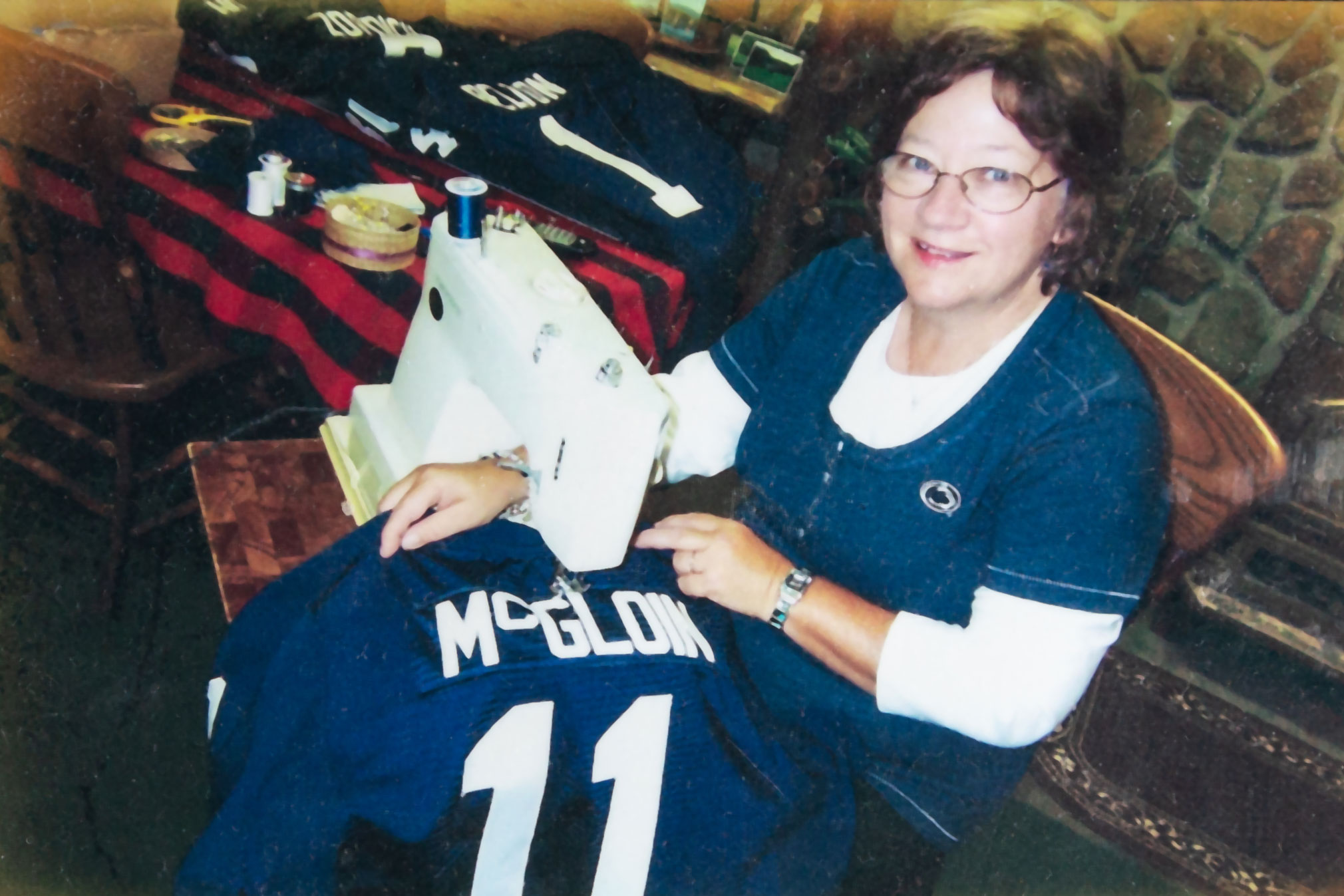 photo of a picture of Caldwell's wife, Karen, sewing a PSU football jersey by Nick Sloff '92 A&A