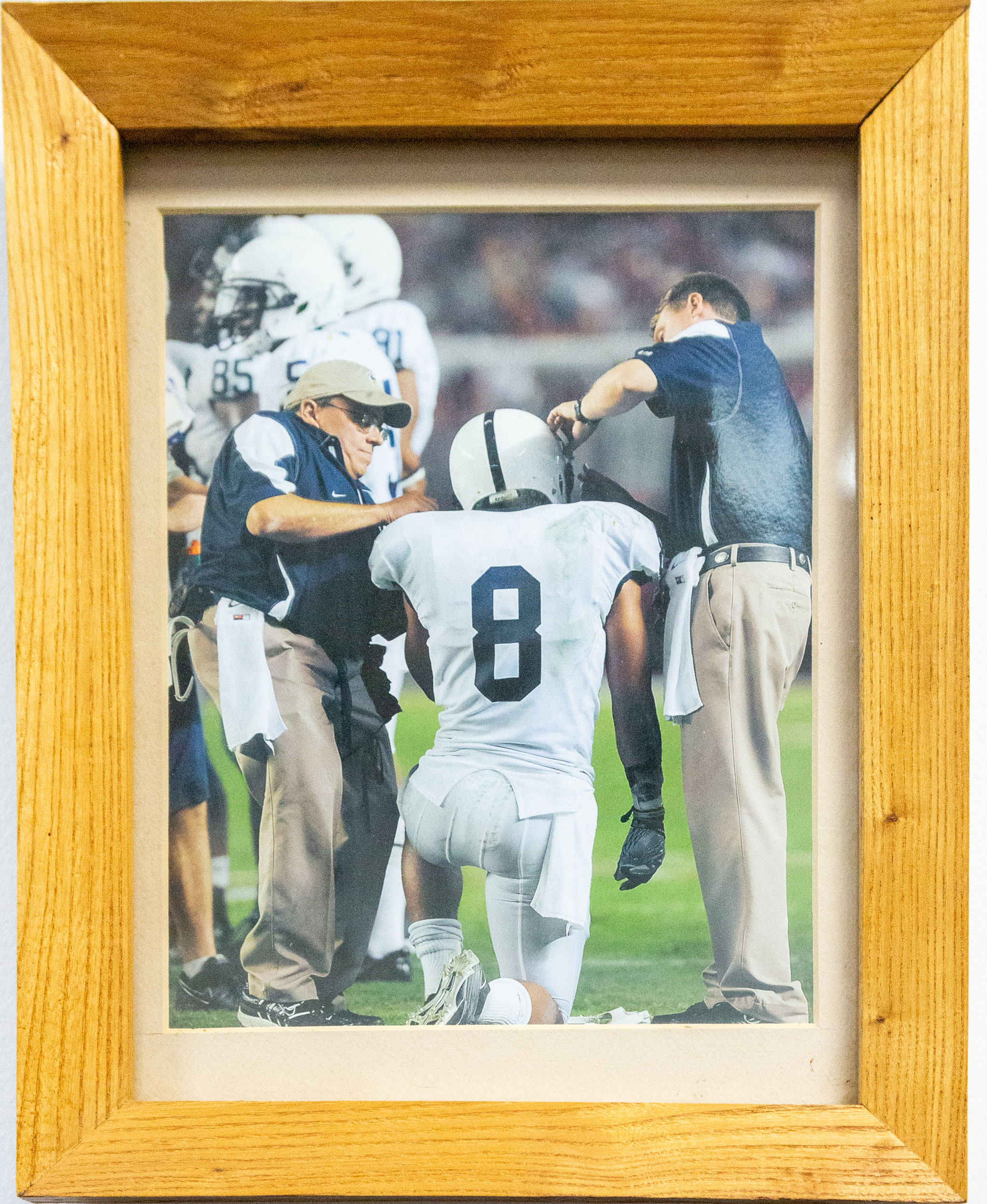 photo of a framed picture of Caldwell and Diehl helping a kneeling player, by Nick Sloff '92 A&A