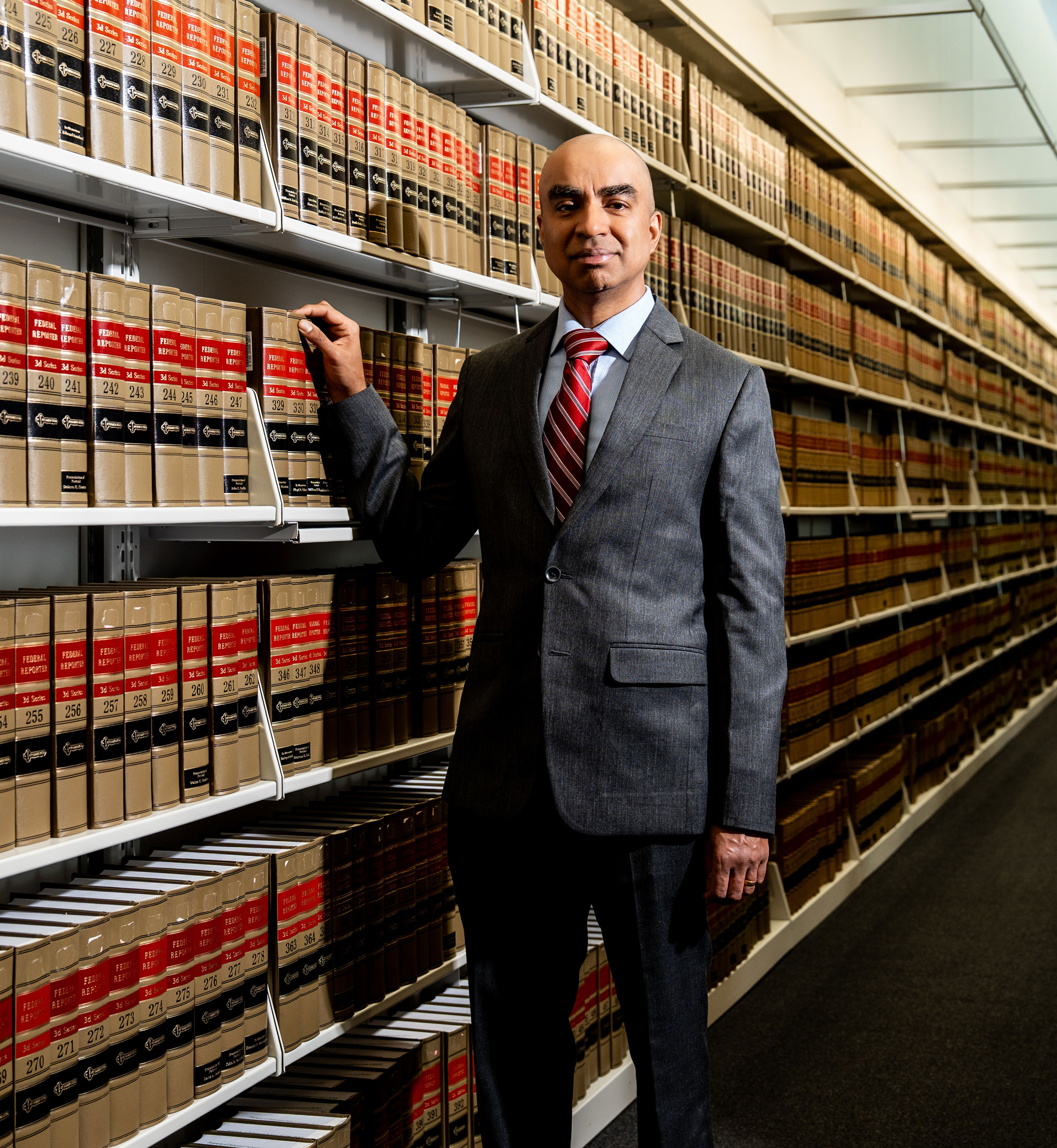 photo of Balachandran in front of a library of law books, photo by Cardoni