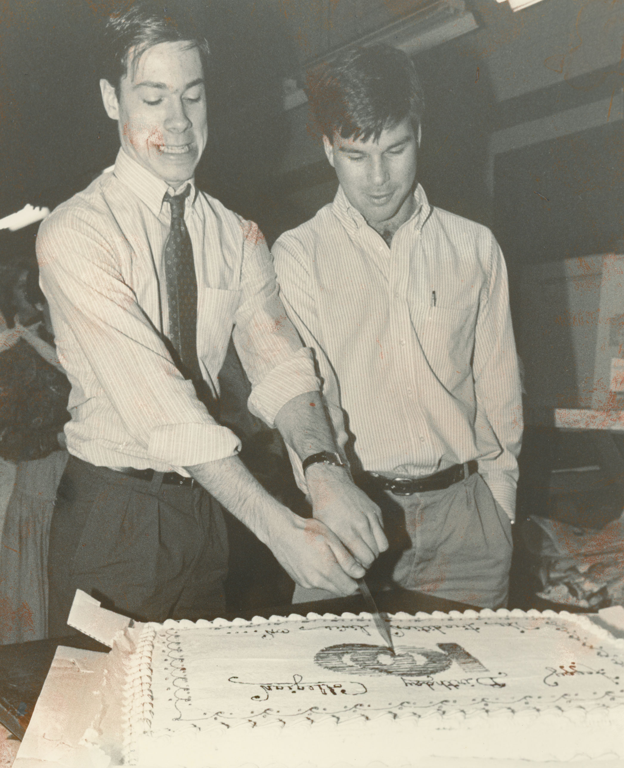 black and white photo of two Collegian staffers cutting a sheet cake, courtesy Collegian