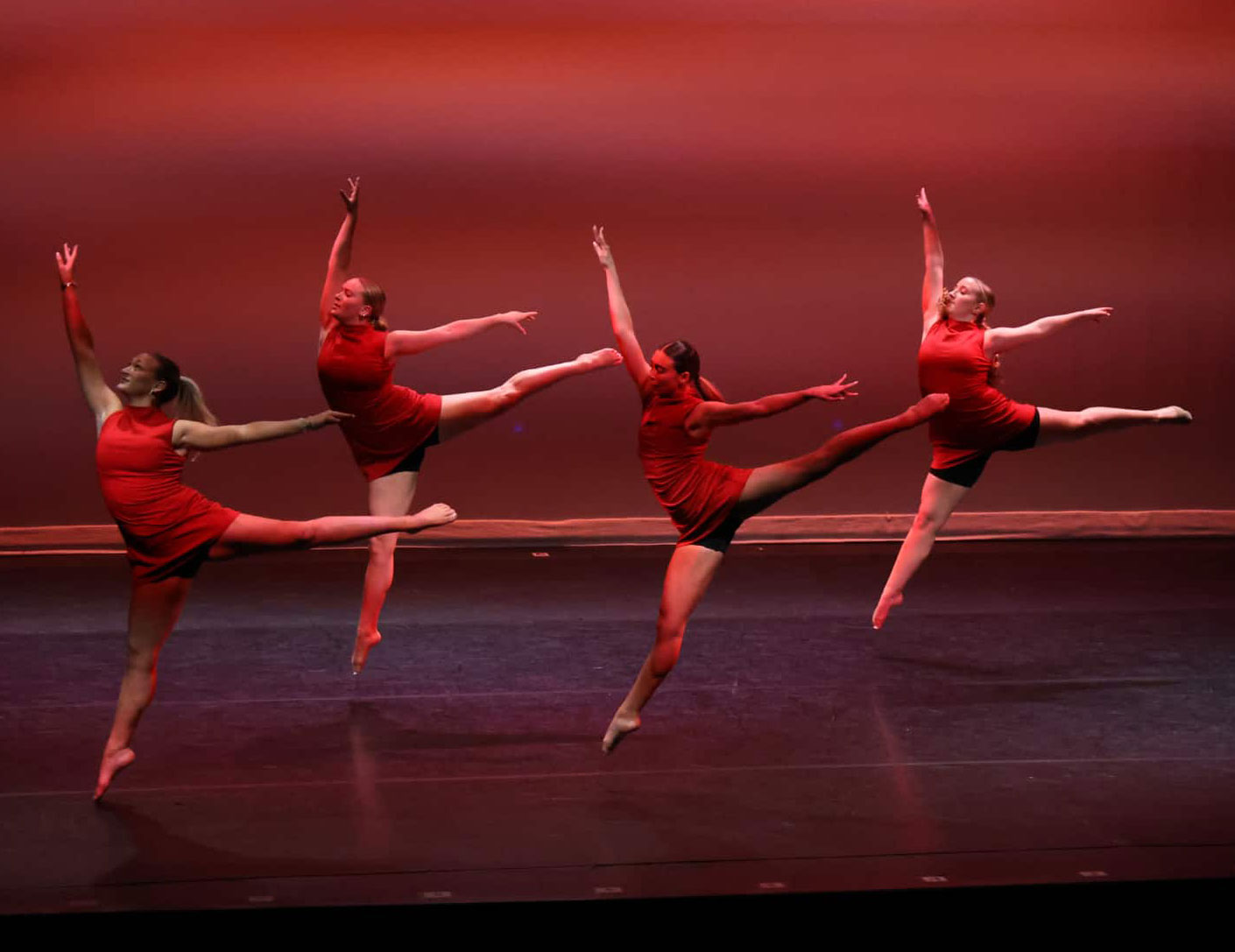 photo of four dancers in red on stage by Savannah Rickard