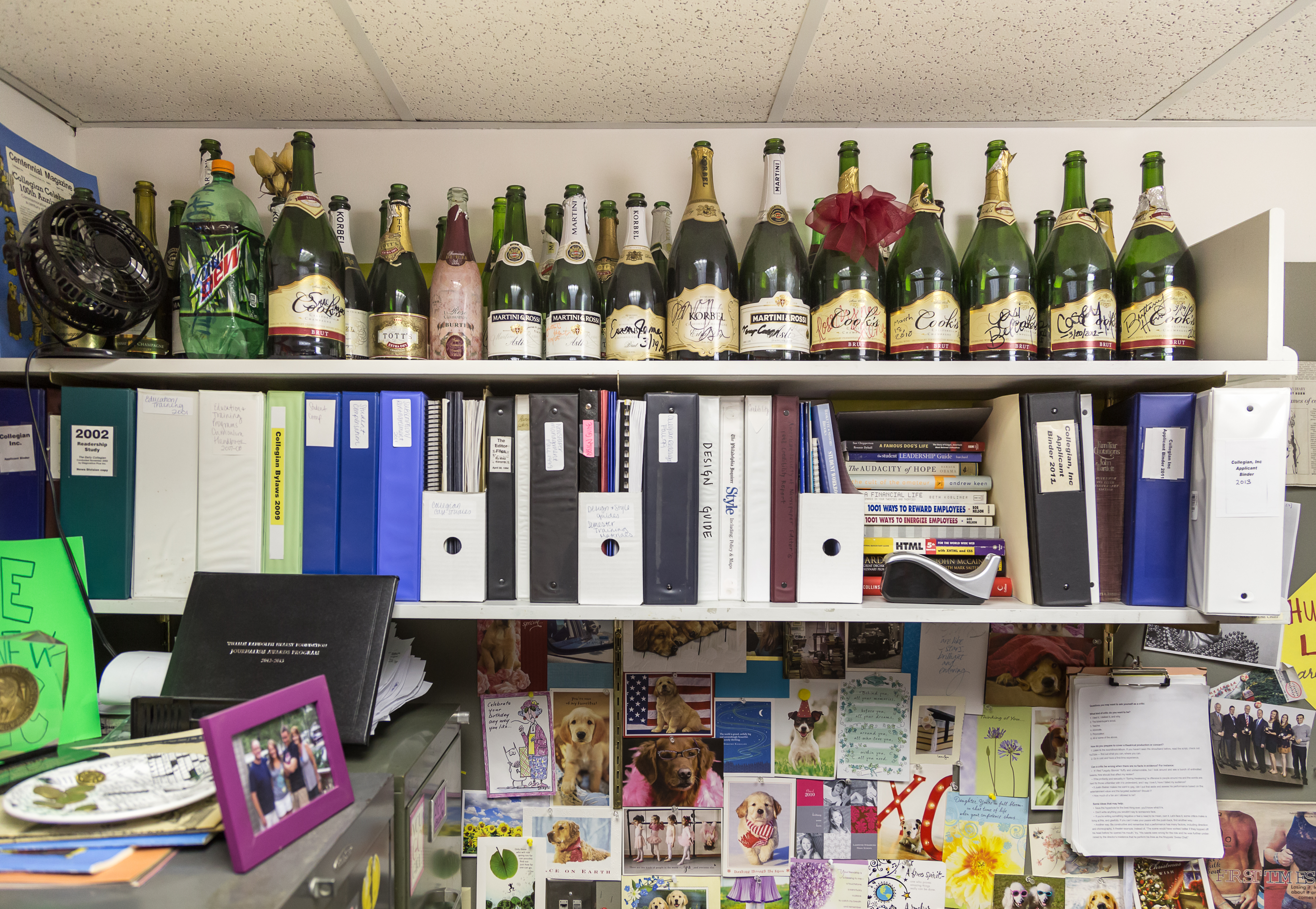 champagne bottles lining shelves full of books and binders in the Collegian newsroom, photo by Nick Sloff '92 A&A