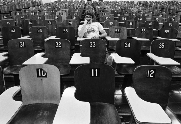 black and white photo of Pat Little in lecture hall in the 70s with numbered wooden seats, photo by Pat Little