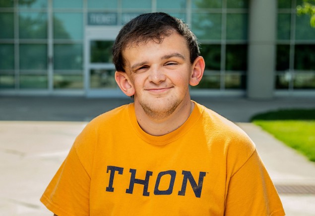 Tucker Haas wearing a yellow THON shirt and standing outside the Bryce Jordan Center by Cardoni