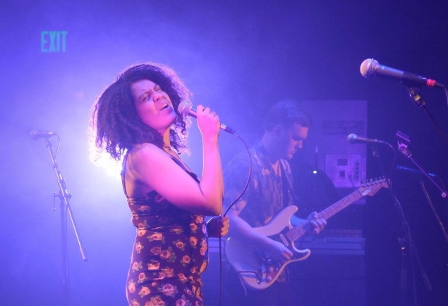 Kat Leverenz singing on a purple-lit stage, courtesy