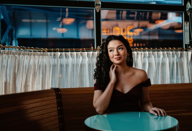 Lisa Rogali seated at a round green table in a cafe, photo by Jiyang Chen