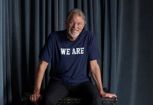 photo of Jonathan Frakes wearing a blue We Are t-shirt and sitting on a theater prop box by Gregg Segal