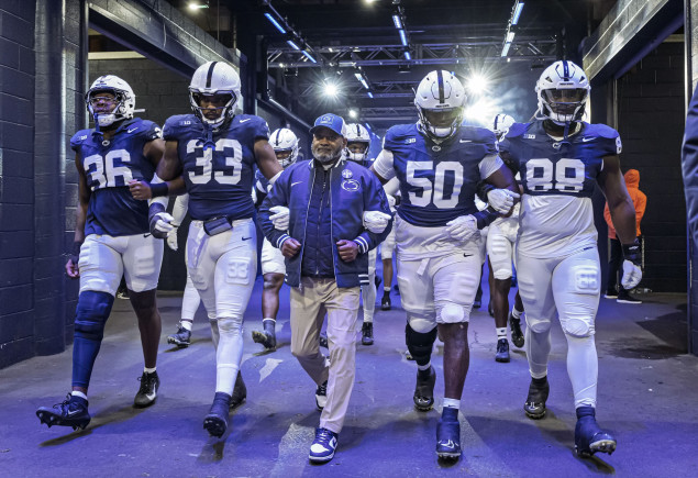 group photo of Smith and players walking onto the field out of a blue tunnel, photo by Mark Selders