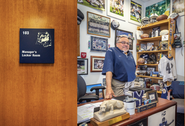 opening spread of Keeper of the Flame featuring a photo of Caldwell's office door and Caldwell standing behind desk inside with PSU football memorabilia on wall and desk by Nick Sloff '92 A&A