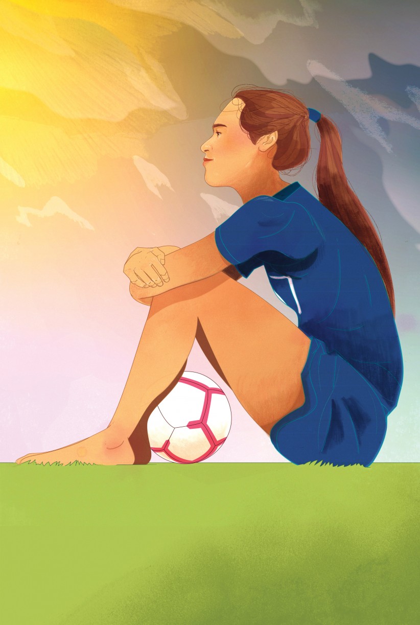 Female soccer player sitting in grass
